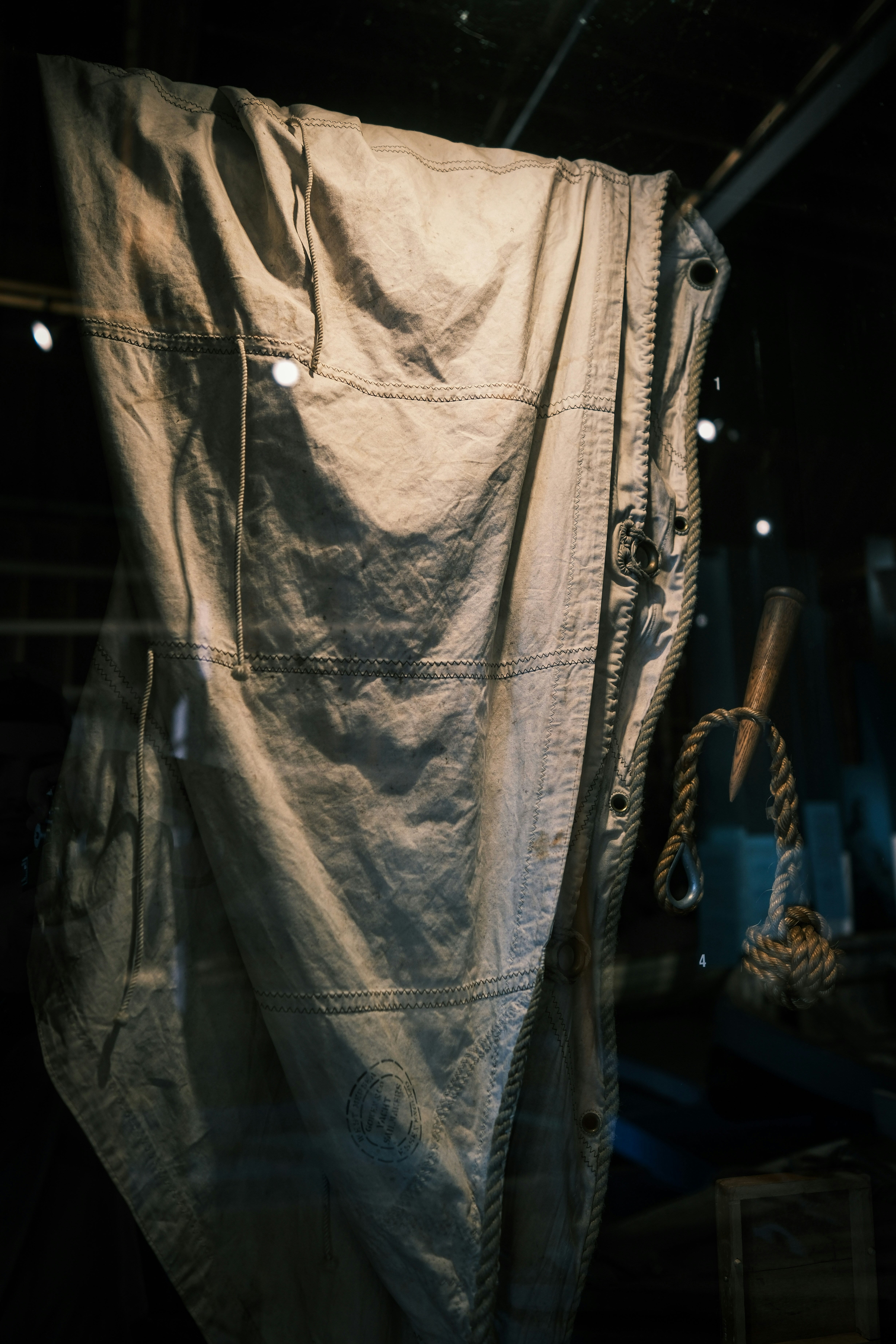 Ein verwittertes Segel hängt in einem schwach beleuchteten Display.