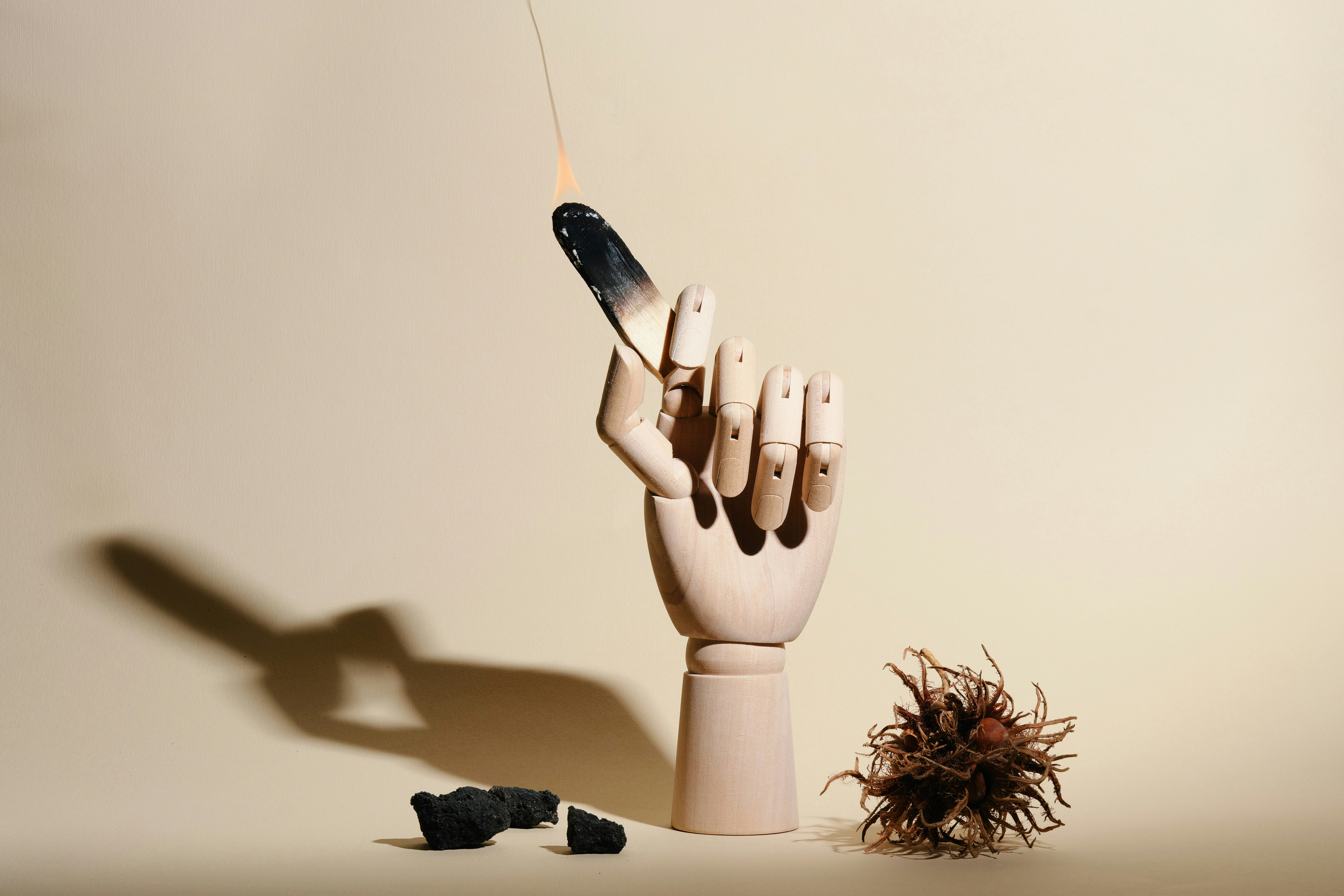 Wooden mannequin hand holding a burning matchstick