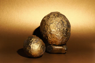 Two rough, golden objects on a golden background.