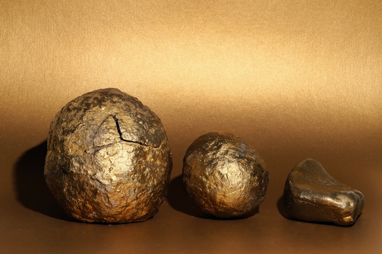 Three metallic gold nuggets on a textured background — the raw material behind every term in this glossary