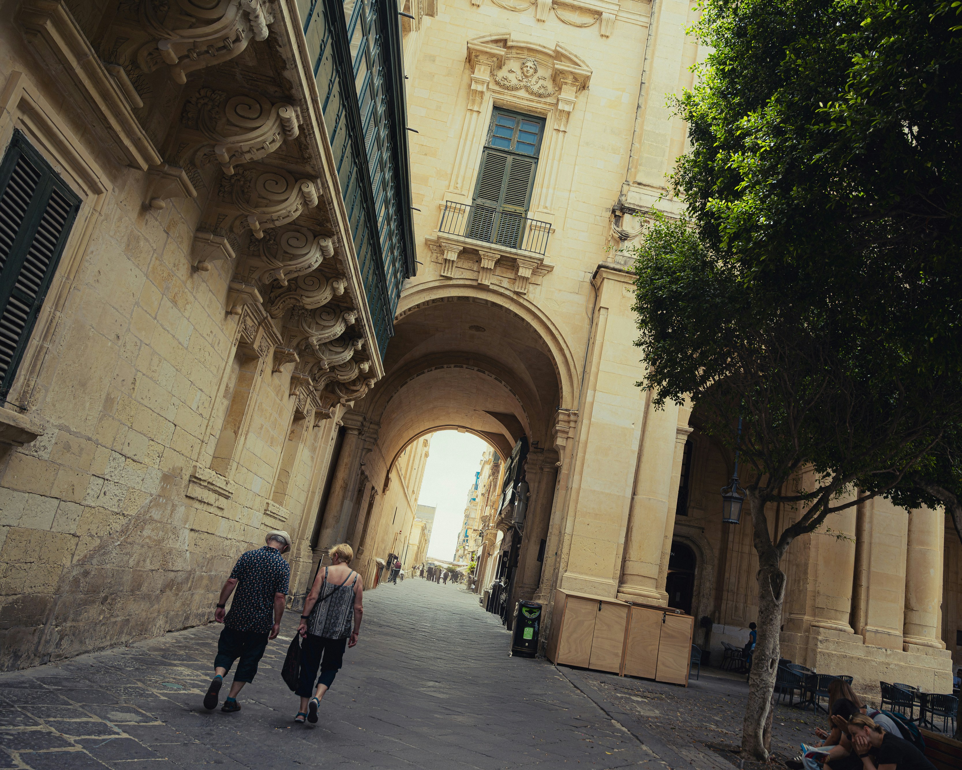 Due persone camminano lungo una stretta strada europea.