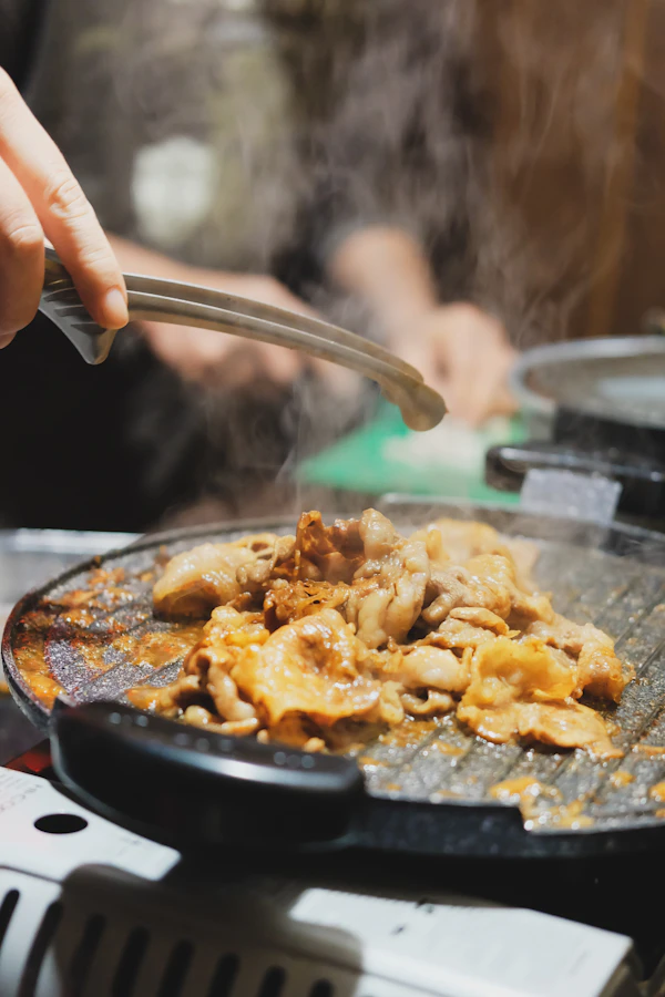 Meat and vegetables cooking on a domed jingisukan grill with steam rising