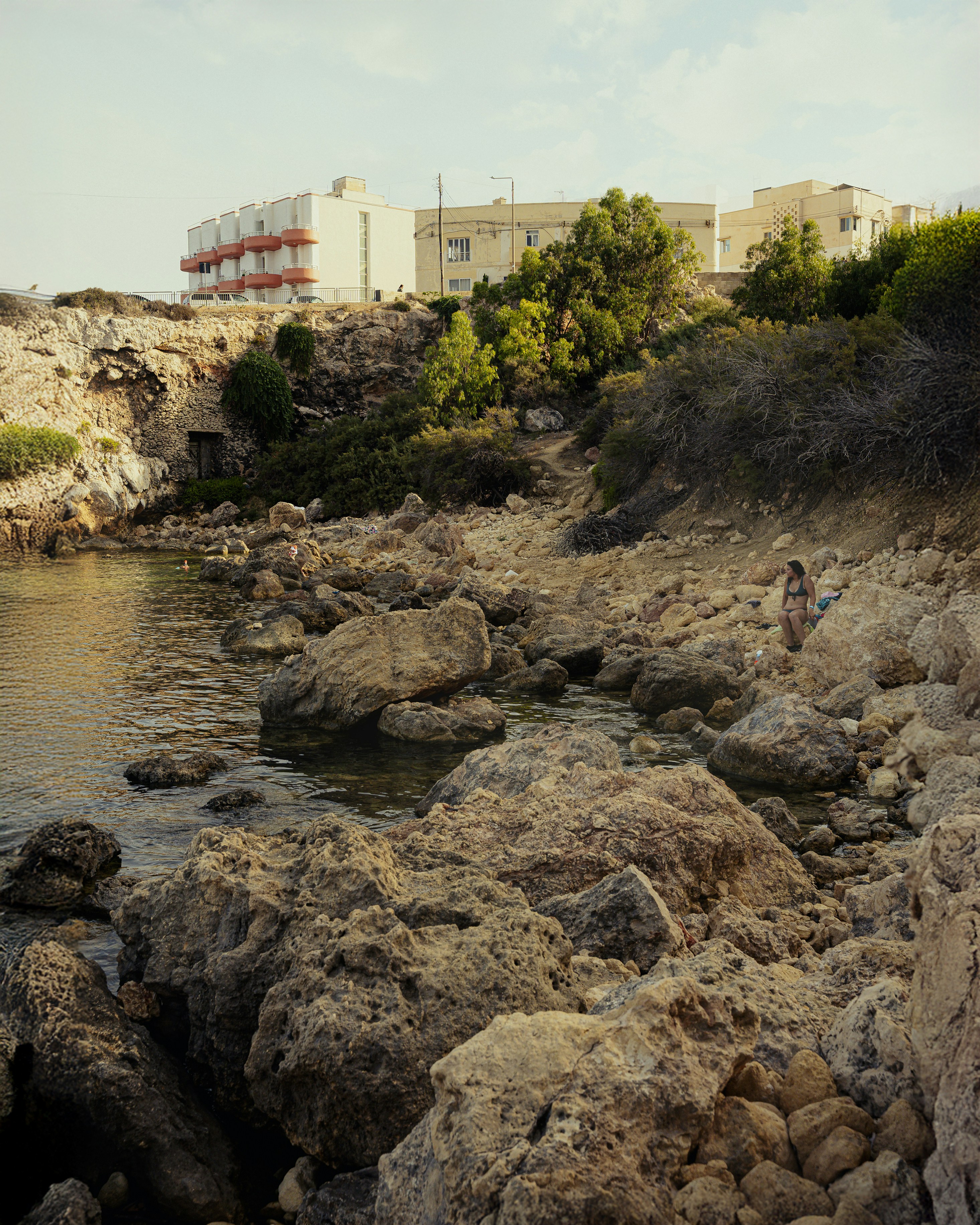 costa rocciosa con una persona e un edificio sullo sfondo.