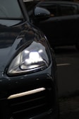 Close-up of a car's illuminated headlight and grille.