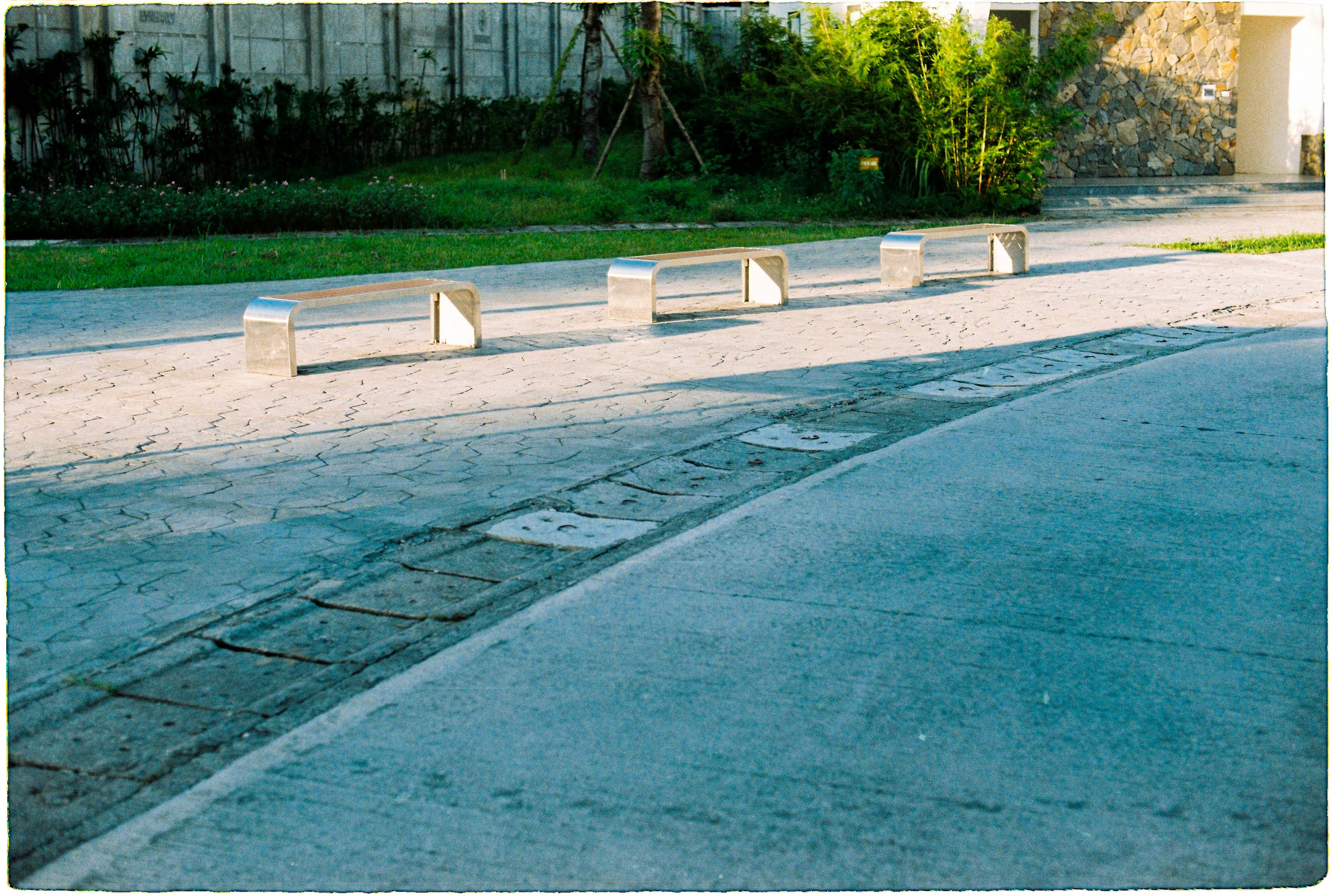 Four modern benches line a paved walkway.