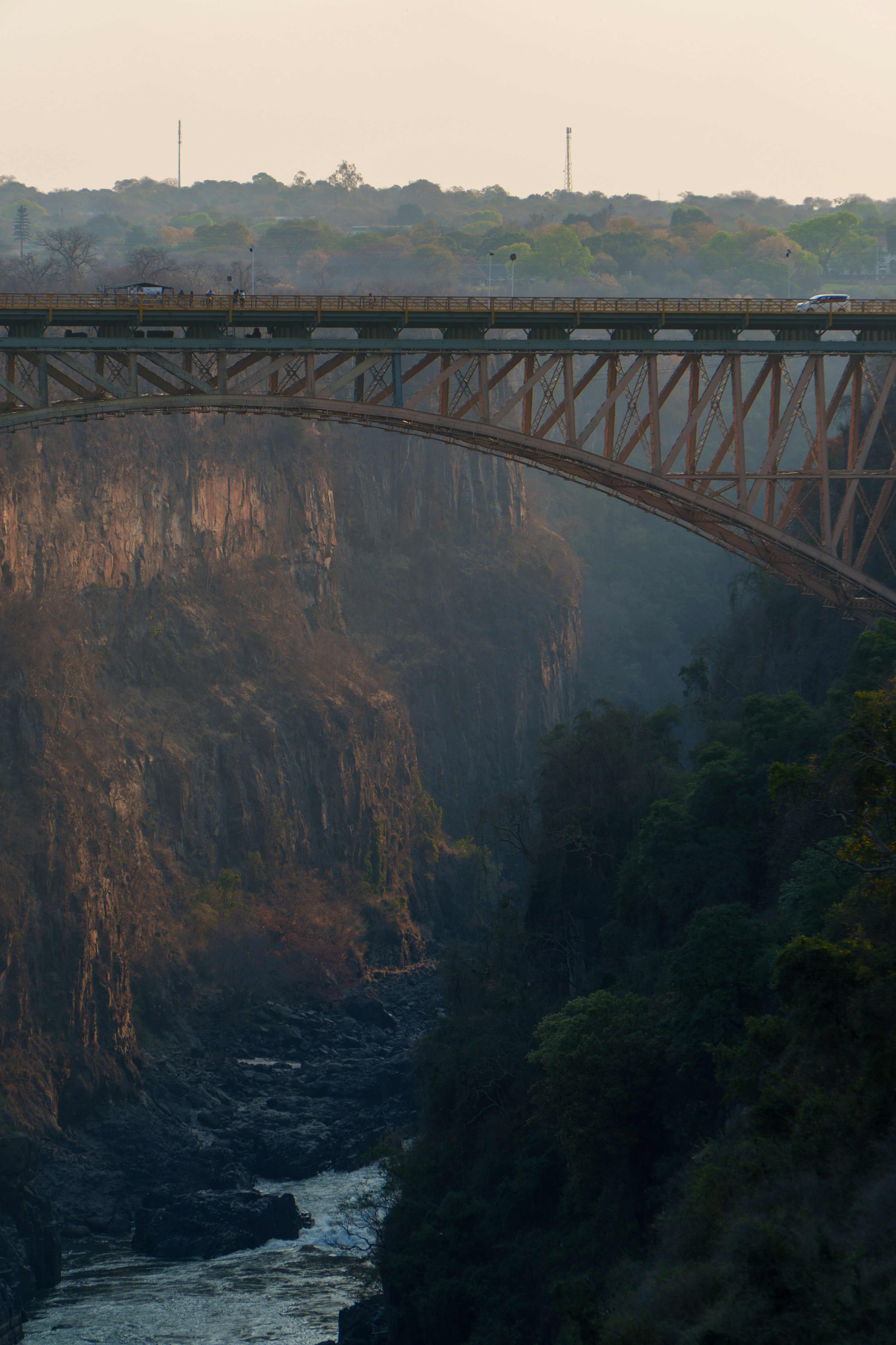 A bridge spans a misty gorge with a river below.