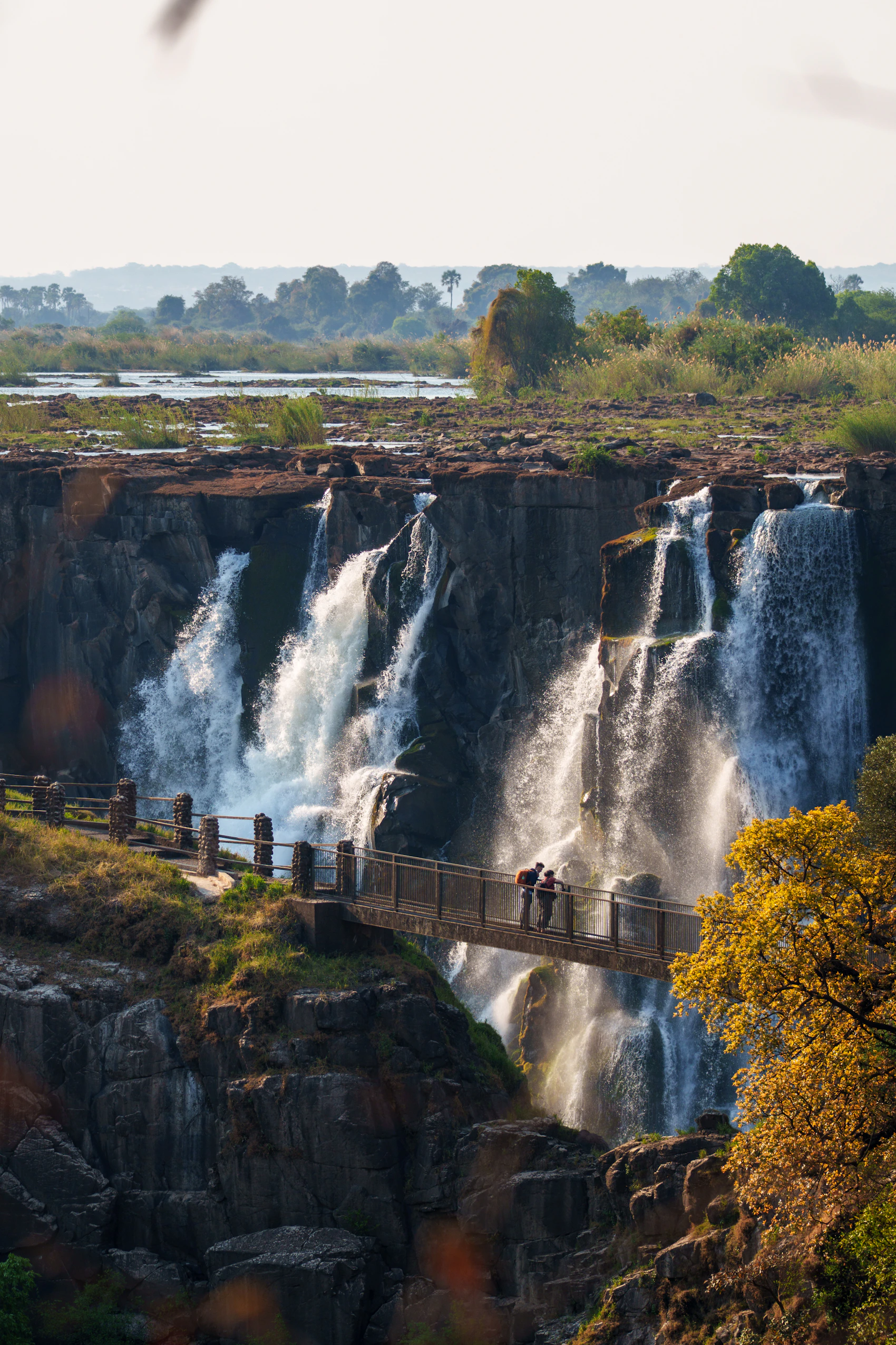 Visitors crossing a viewpoint bridge beside the powerful Victoria Falls