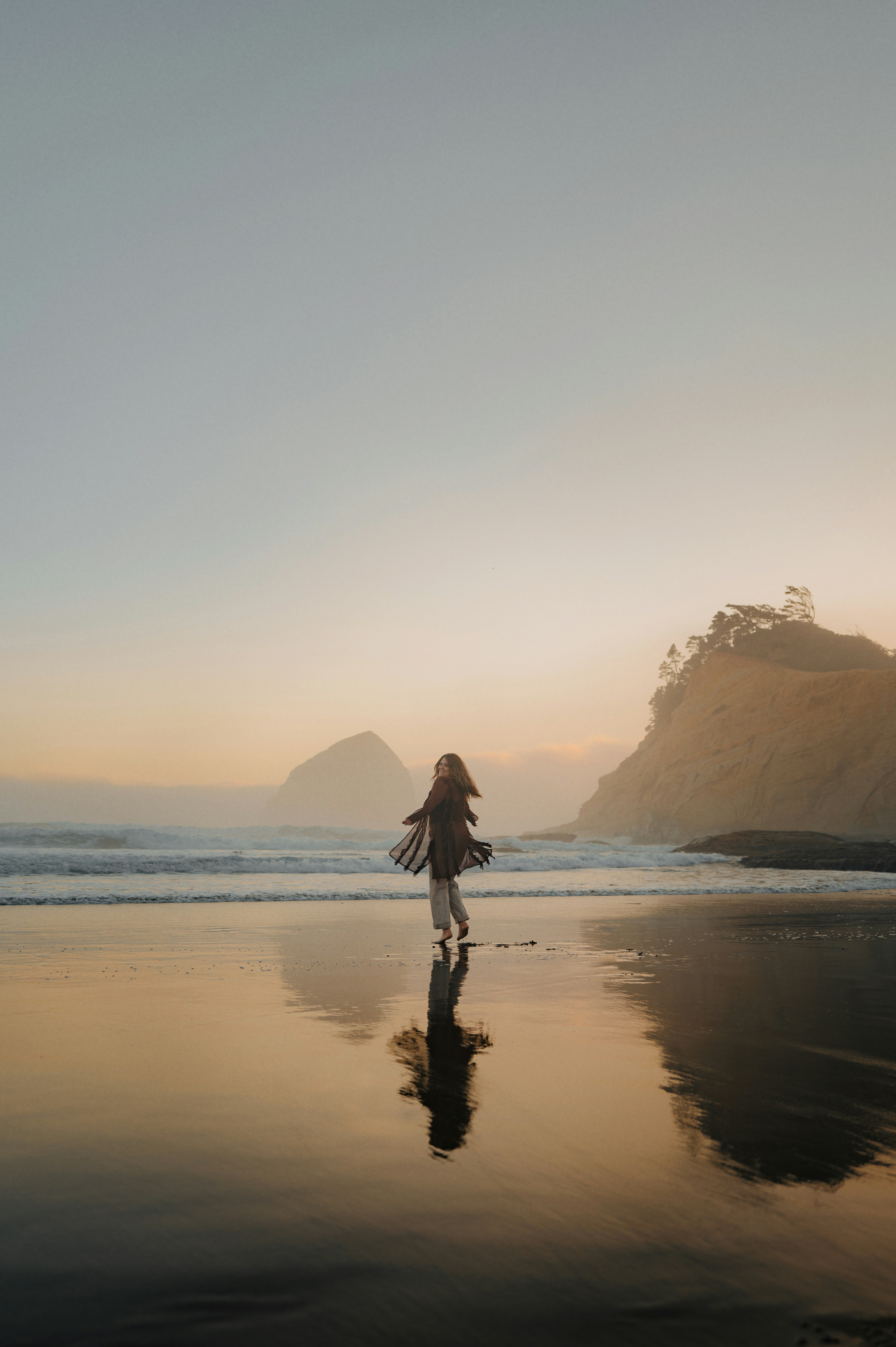 Woman twirling on a beach at sunset