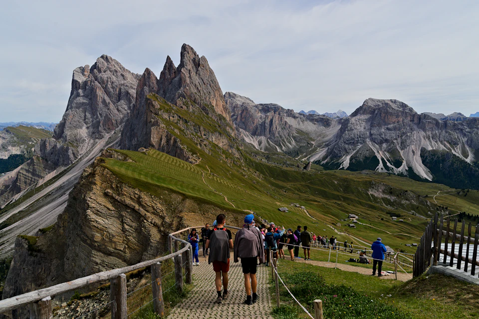 Group of people walking on wooden boardwalk ascending up a mountain with scenic views