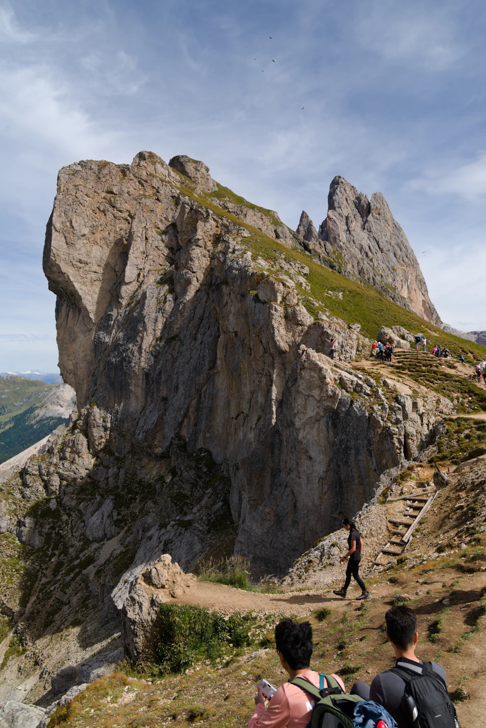 Group of hikers ascending rocky mountain trail with backpacks and camera in hand