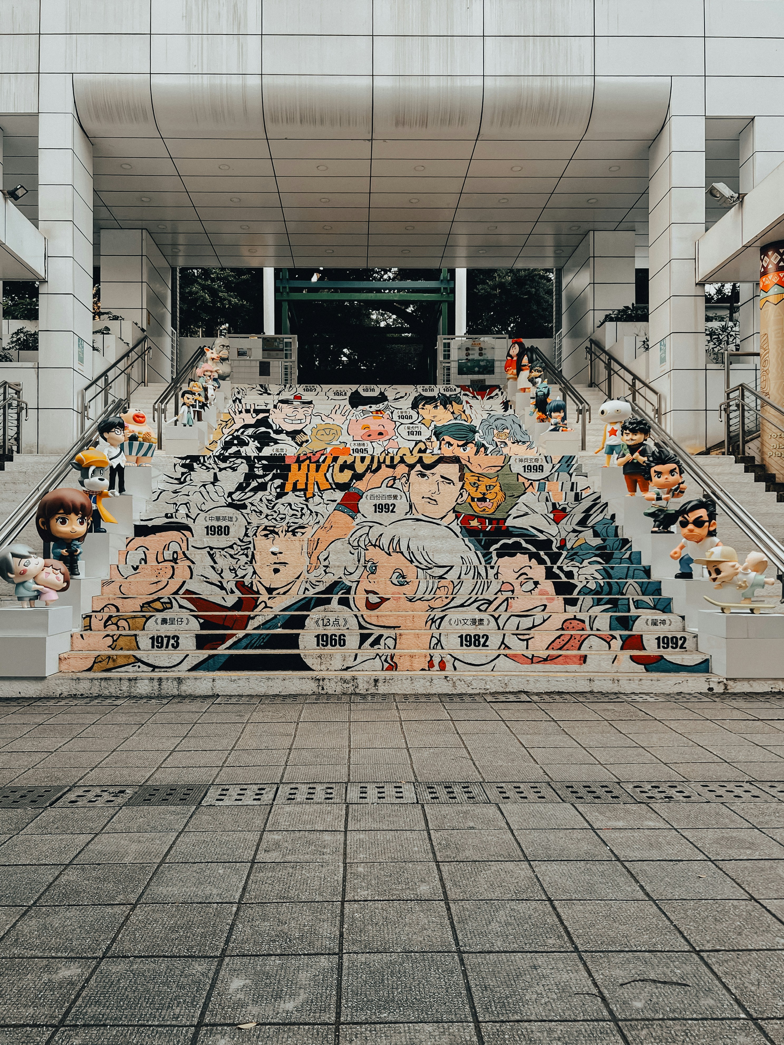 Colorful mural of faces and figures on outdoor stairs.