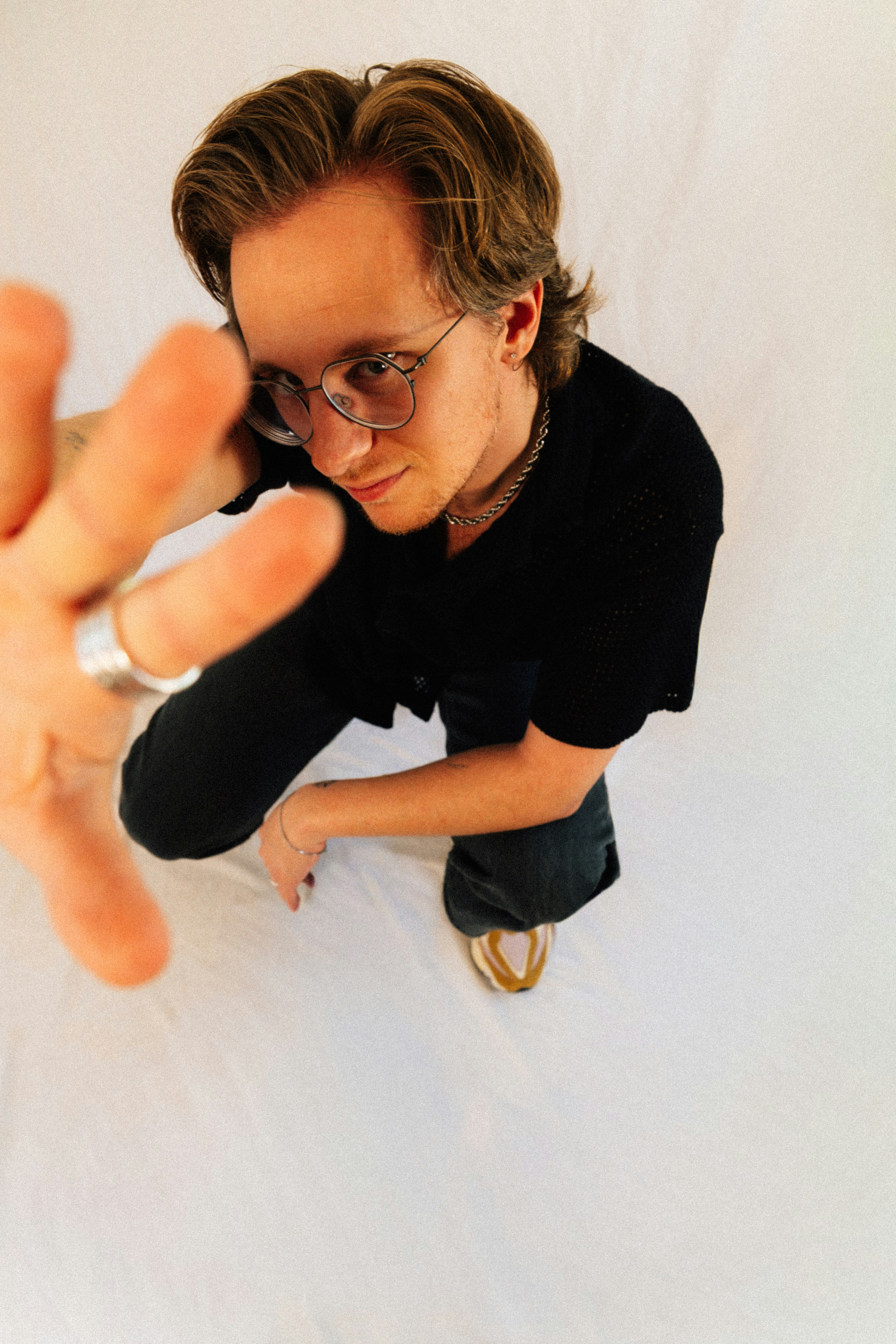 Man in black shirt and glasses reaches forward.