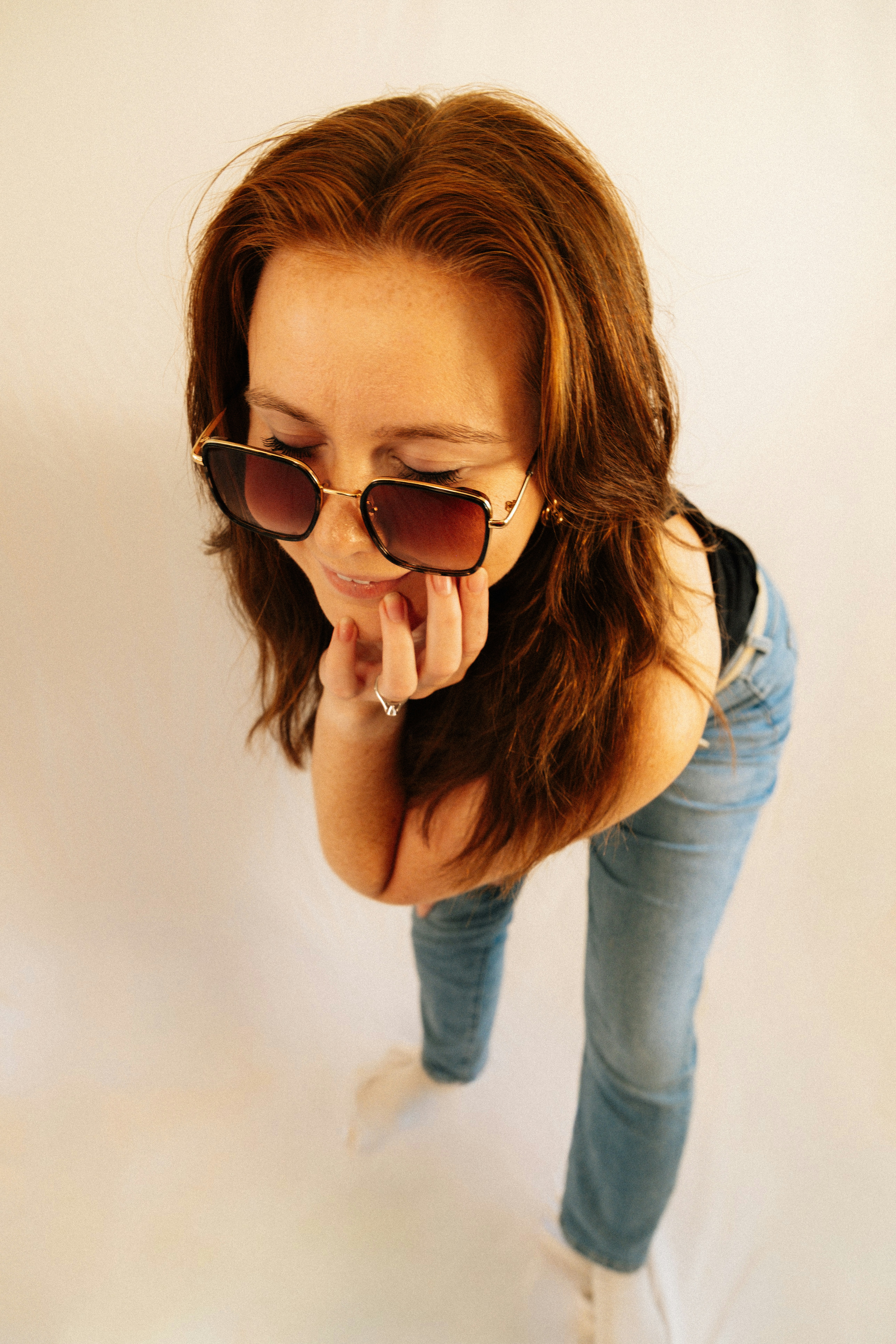 Woman wearing sunglasses and jeans on a white background