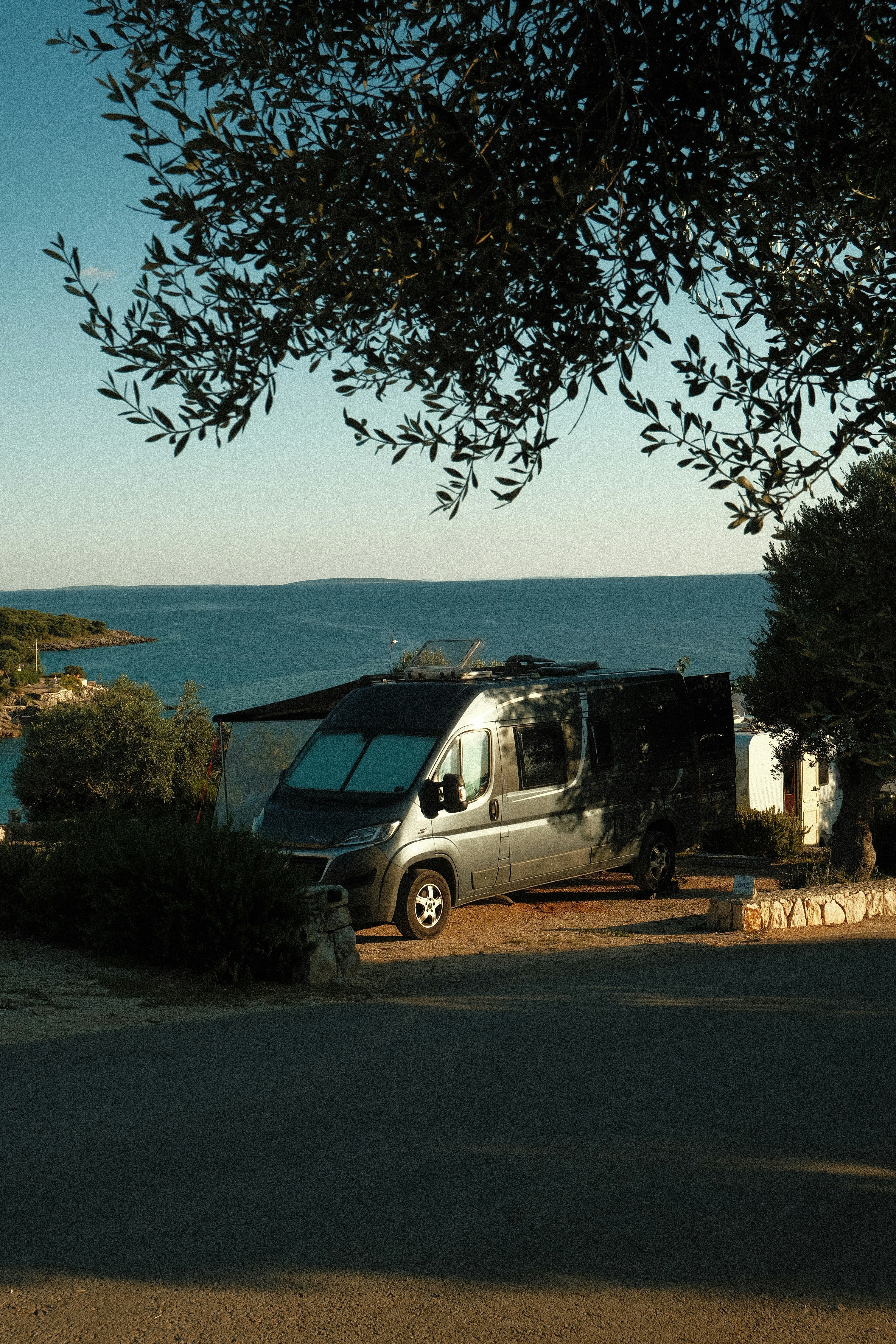 Campervan parked by the sea under trees