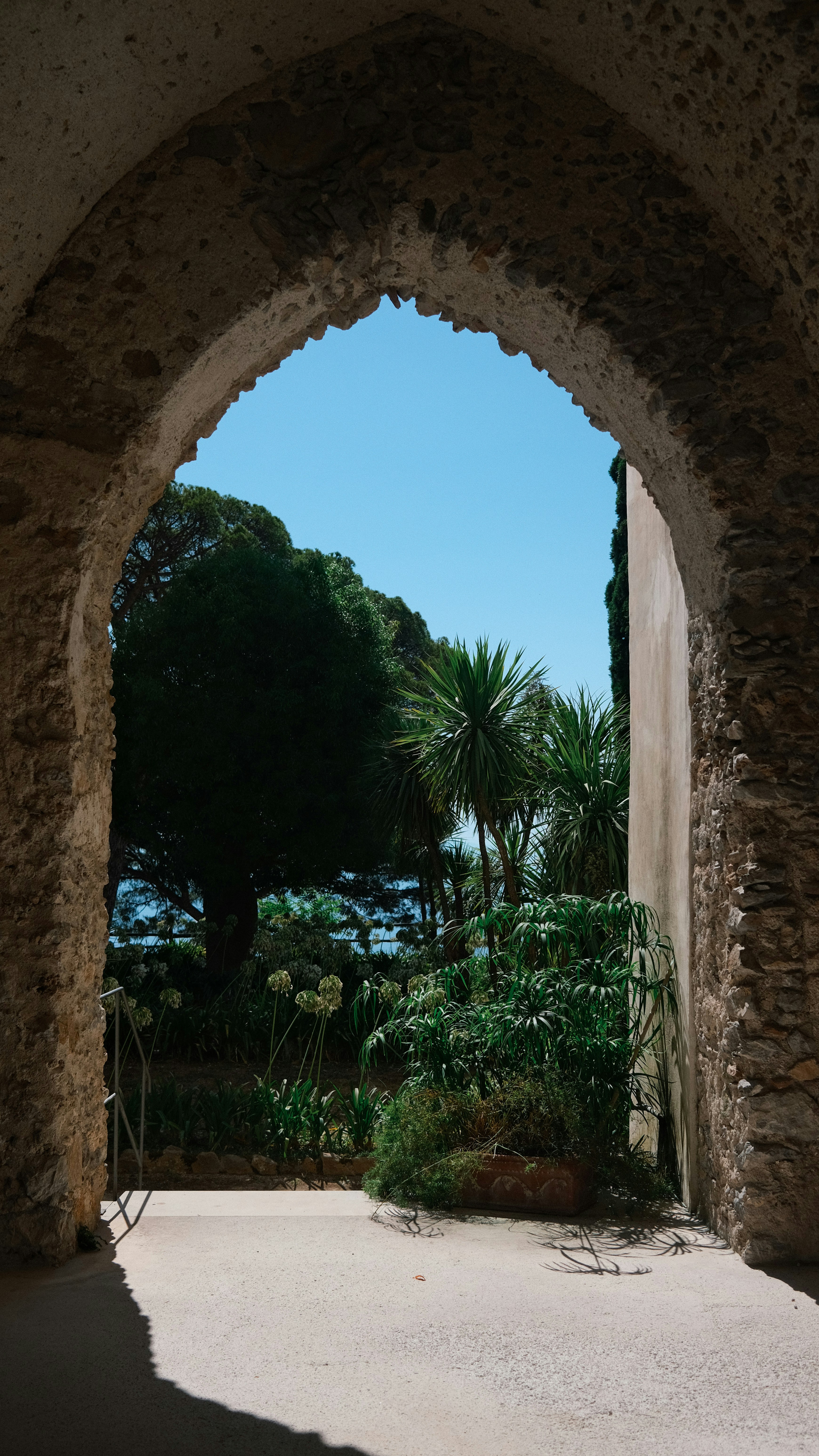 View through an archway to a sunny garden and ocean.