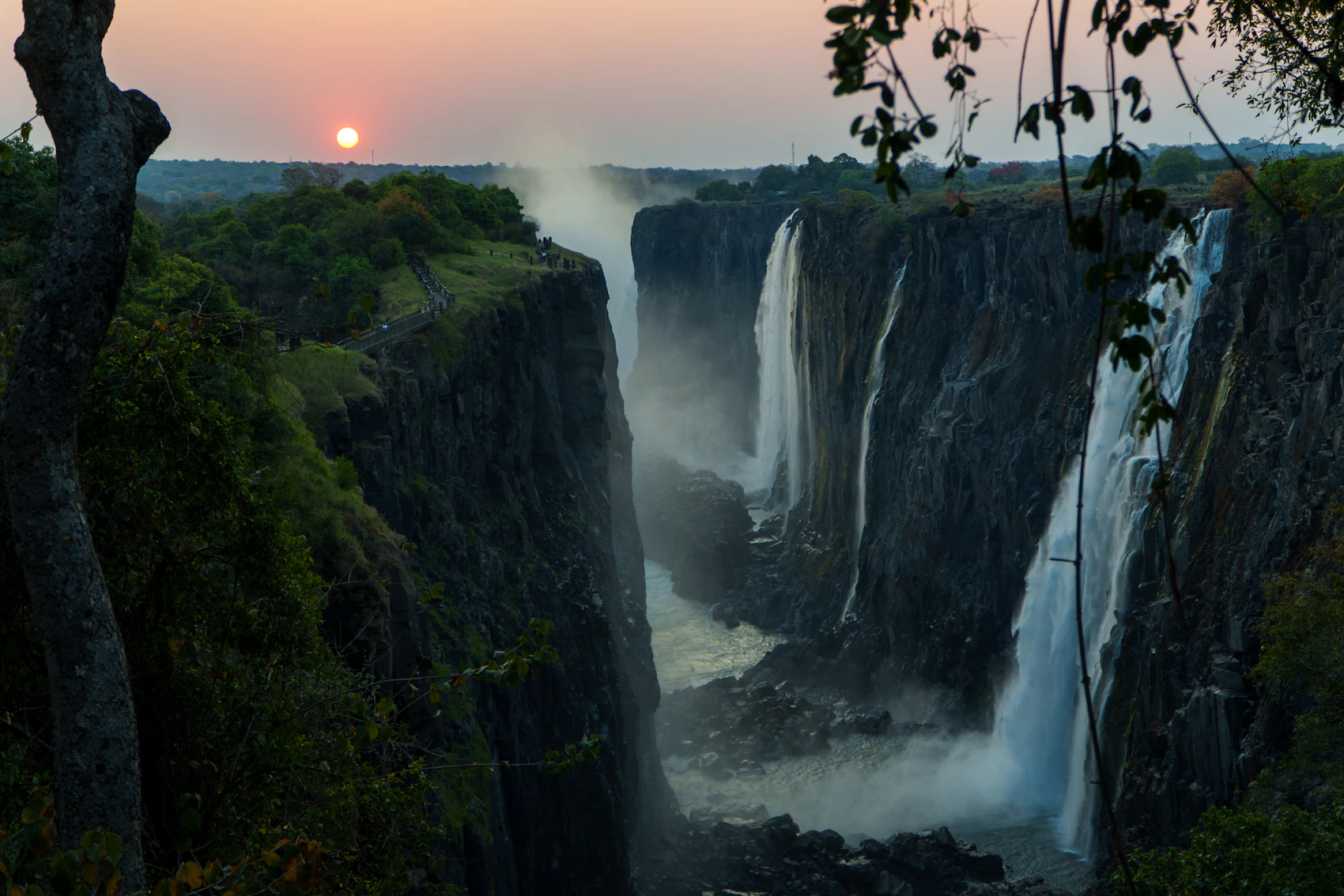 Victoria Falls dropping through green cliffs in Zimbabwe at sunrise