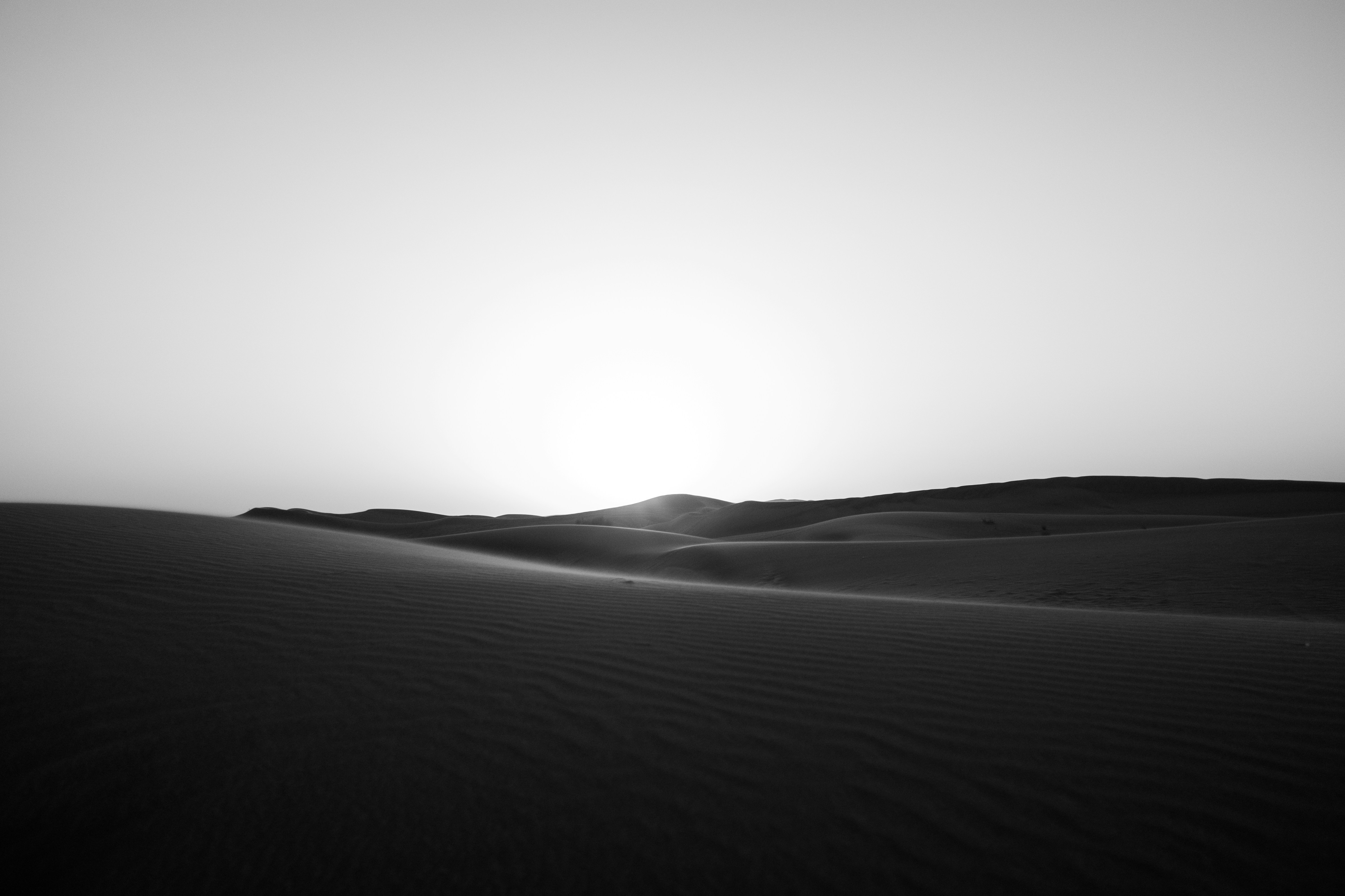Desert sand dunes under a bright sky