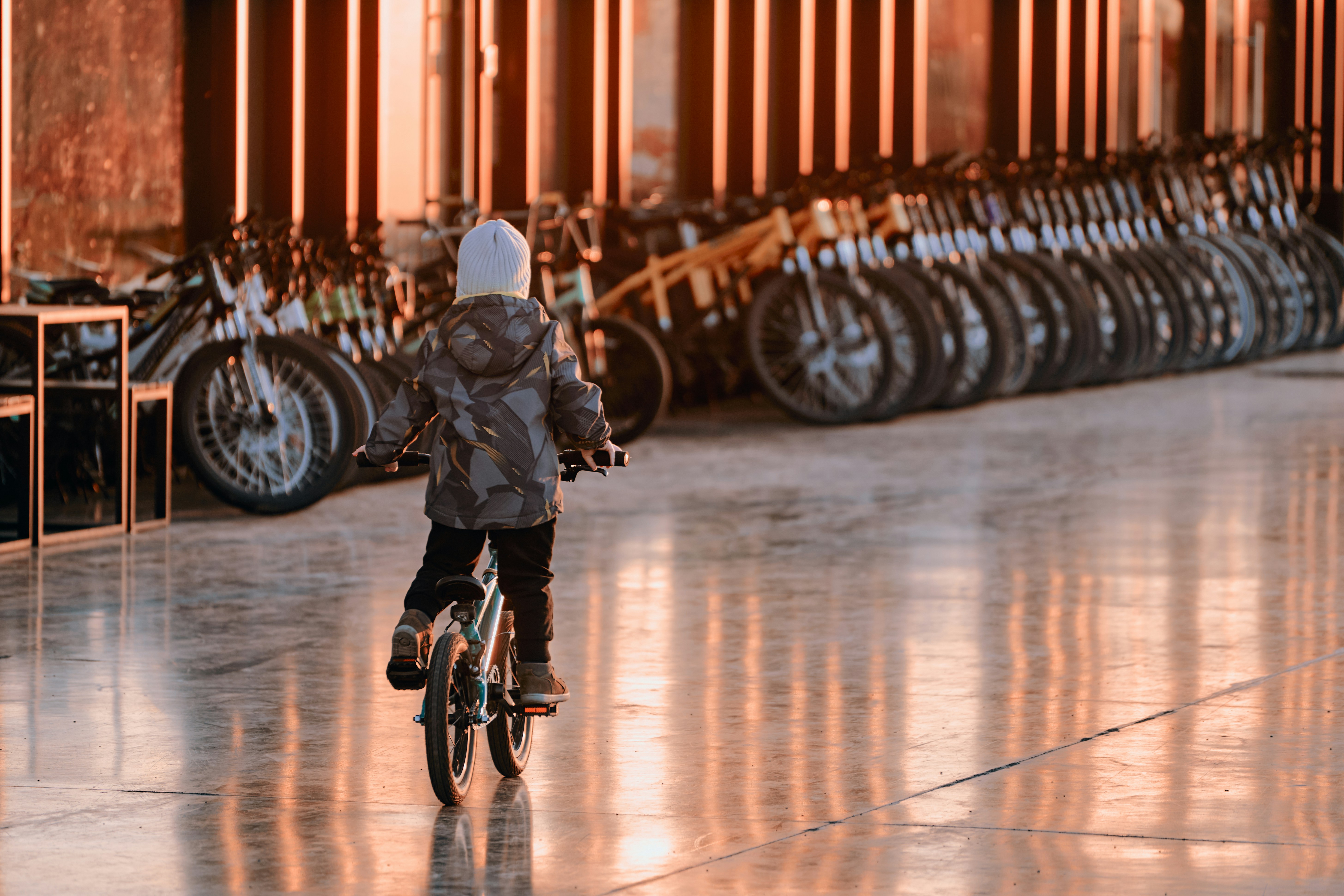 Child riding a bicycle in a row of parked bicycles.