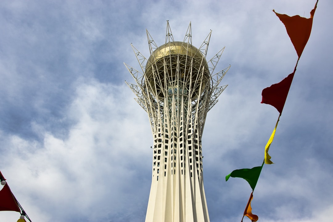 Bayterek tower with colorful flags against cloudy sky