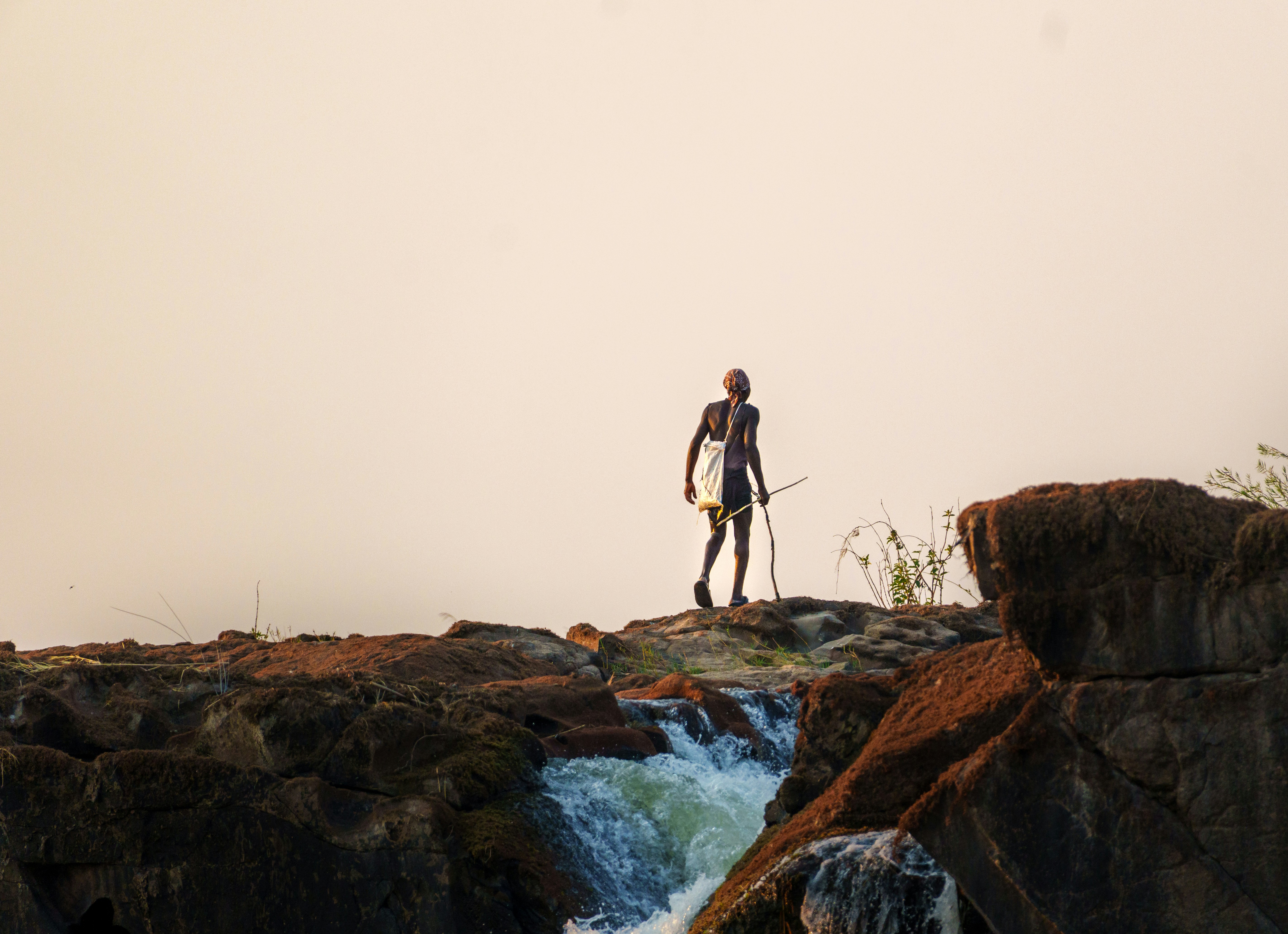 Man standing on rocks overlooking waterfall
