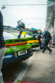 Race cars in pit lane with crew members around