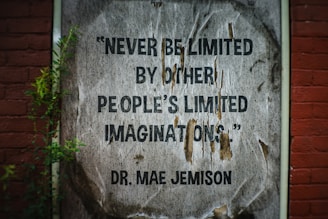 Quote on a weathered poster on brick wall.