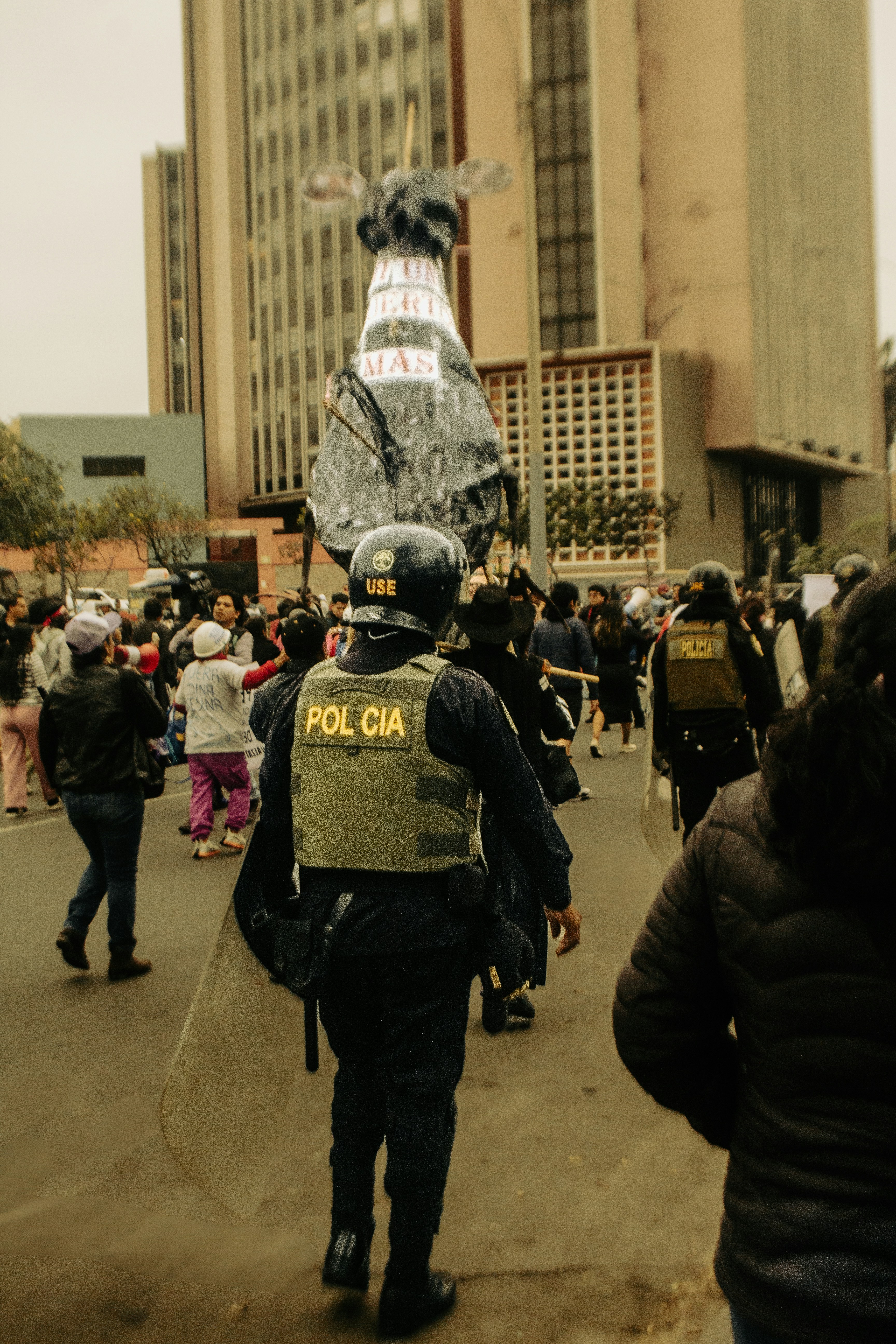 Police officers with riot gear in a street protest.