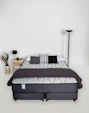 A bed with a mattress, pillows, and blanket