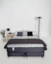 A bed with a mattress, pillows, and blanket