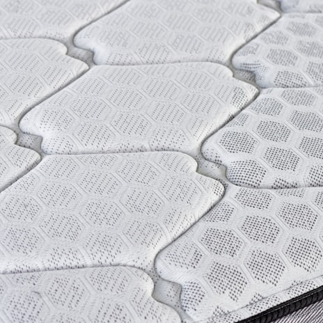 Close-up of a quilted mattress surface with hexagonal pattern.