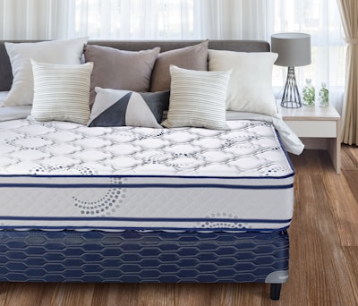 A neatly made bed with a patterned mattress and pillows.