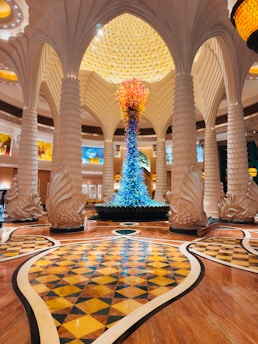 Grand hotel lobby with ornate columns and colorful sculpture.