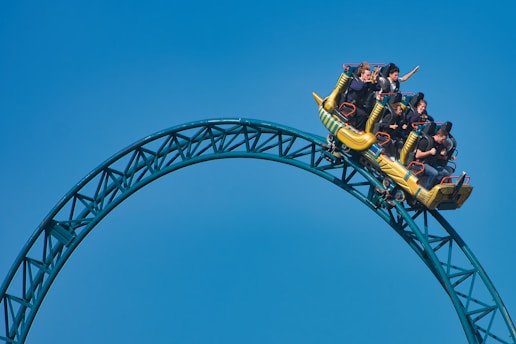 People riding a yellow roller coaster on a loop.