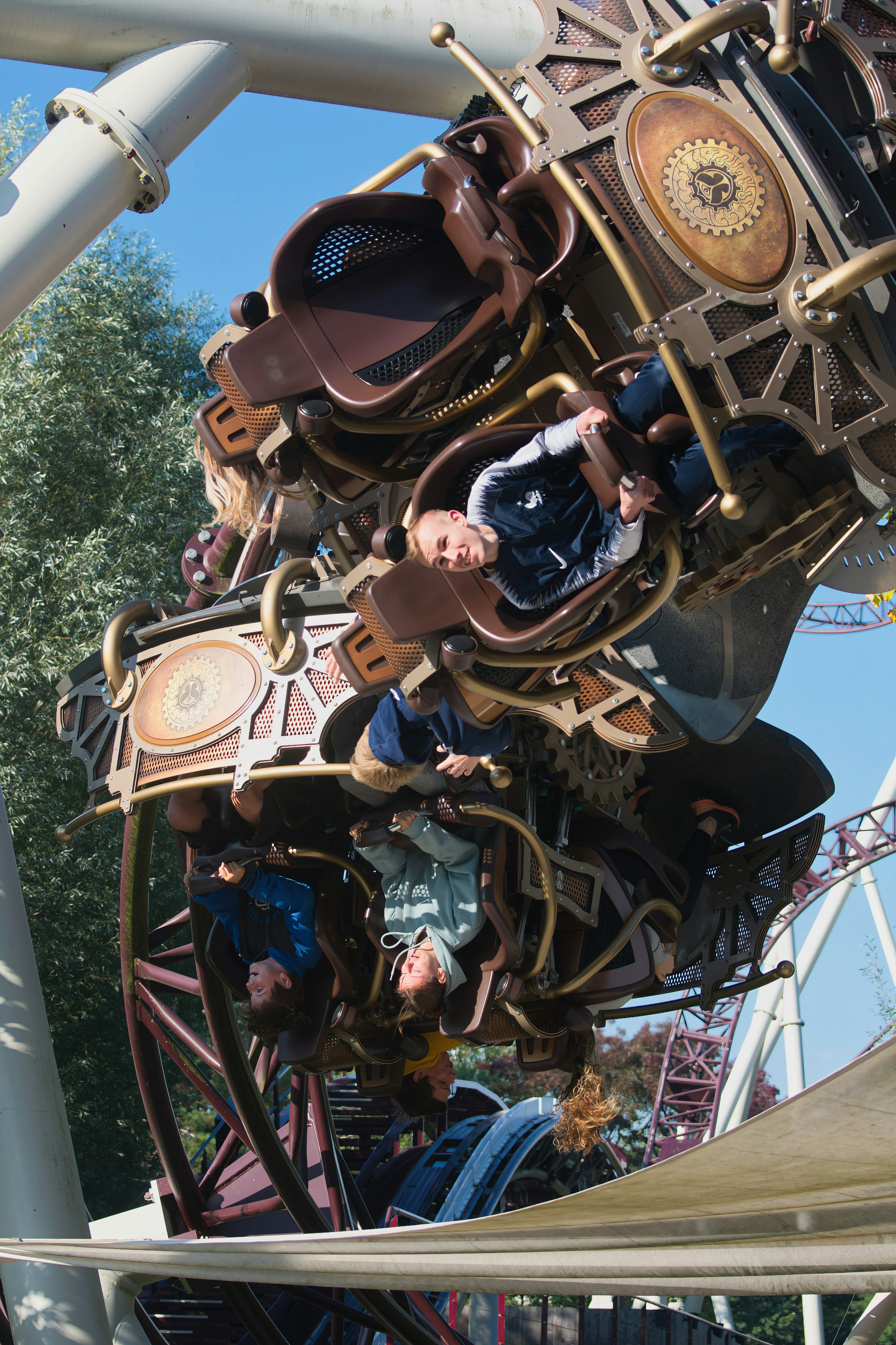 Pessoas andando em uma montanha-russa steampunk complexa de cabeça para baixo.