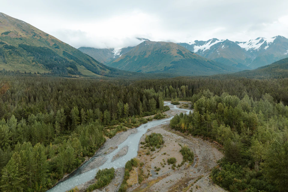 River and forest below mountain peaks in Alaska