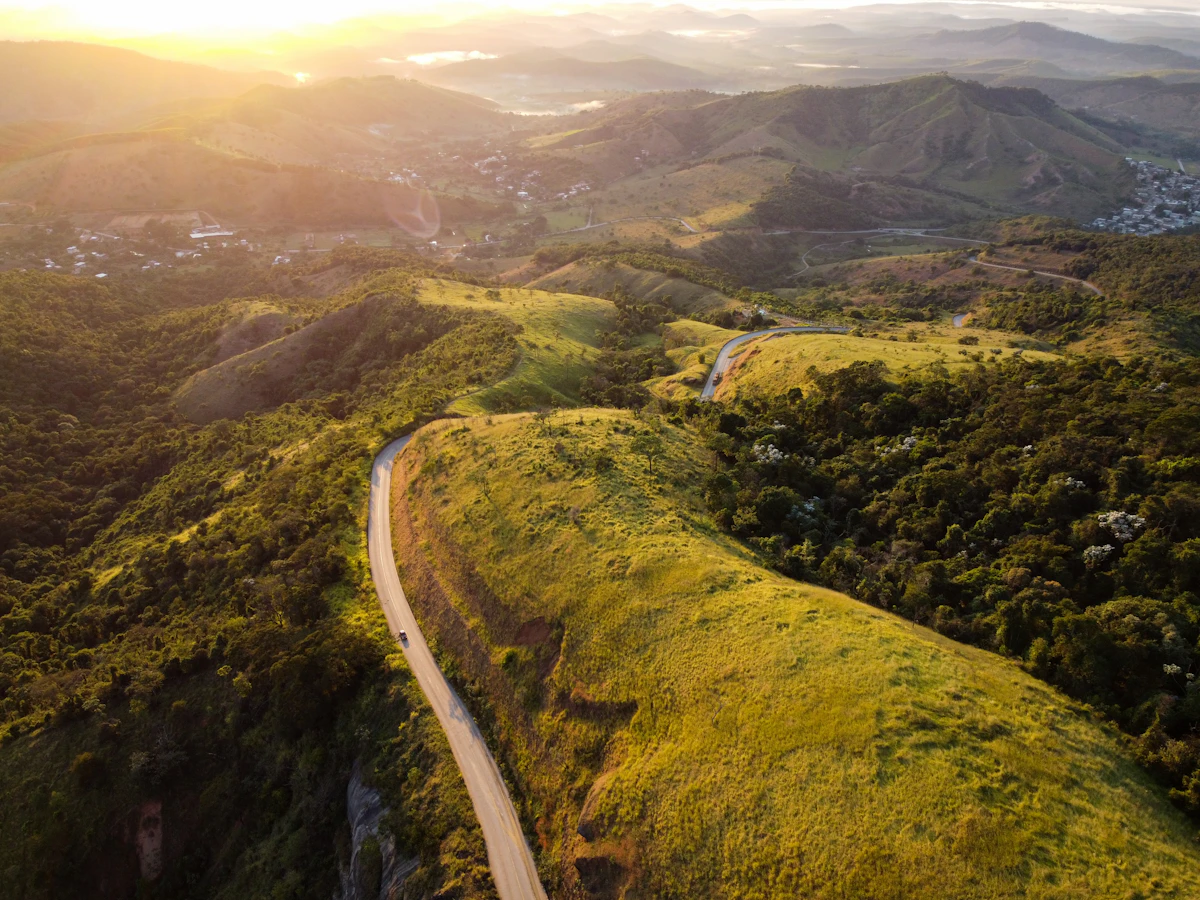 Aerial winding road through green French hills at golden hour