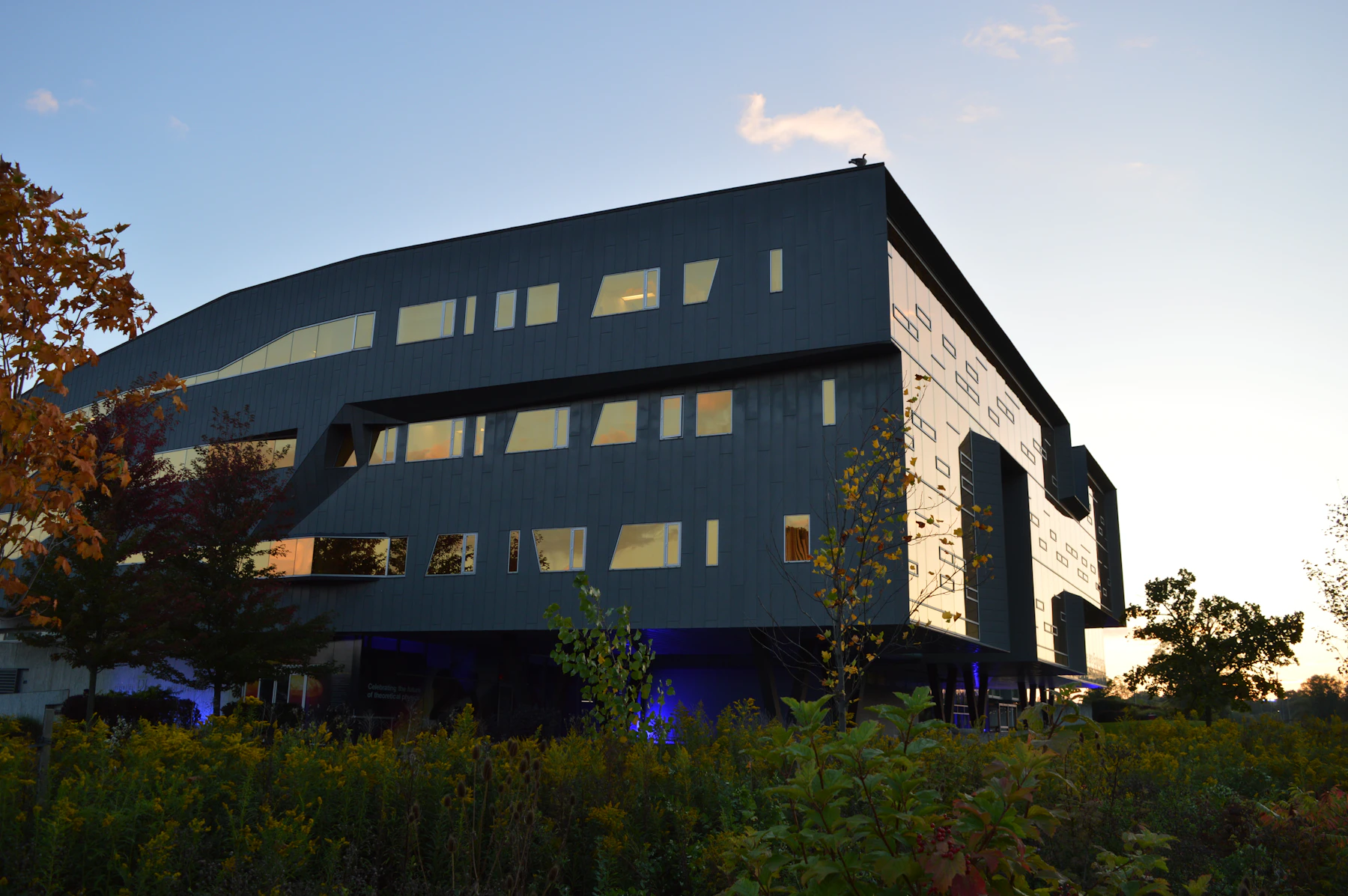 A contemporary building with a mirrored golden facade at dusk