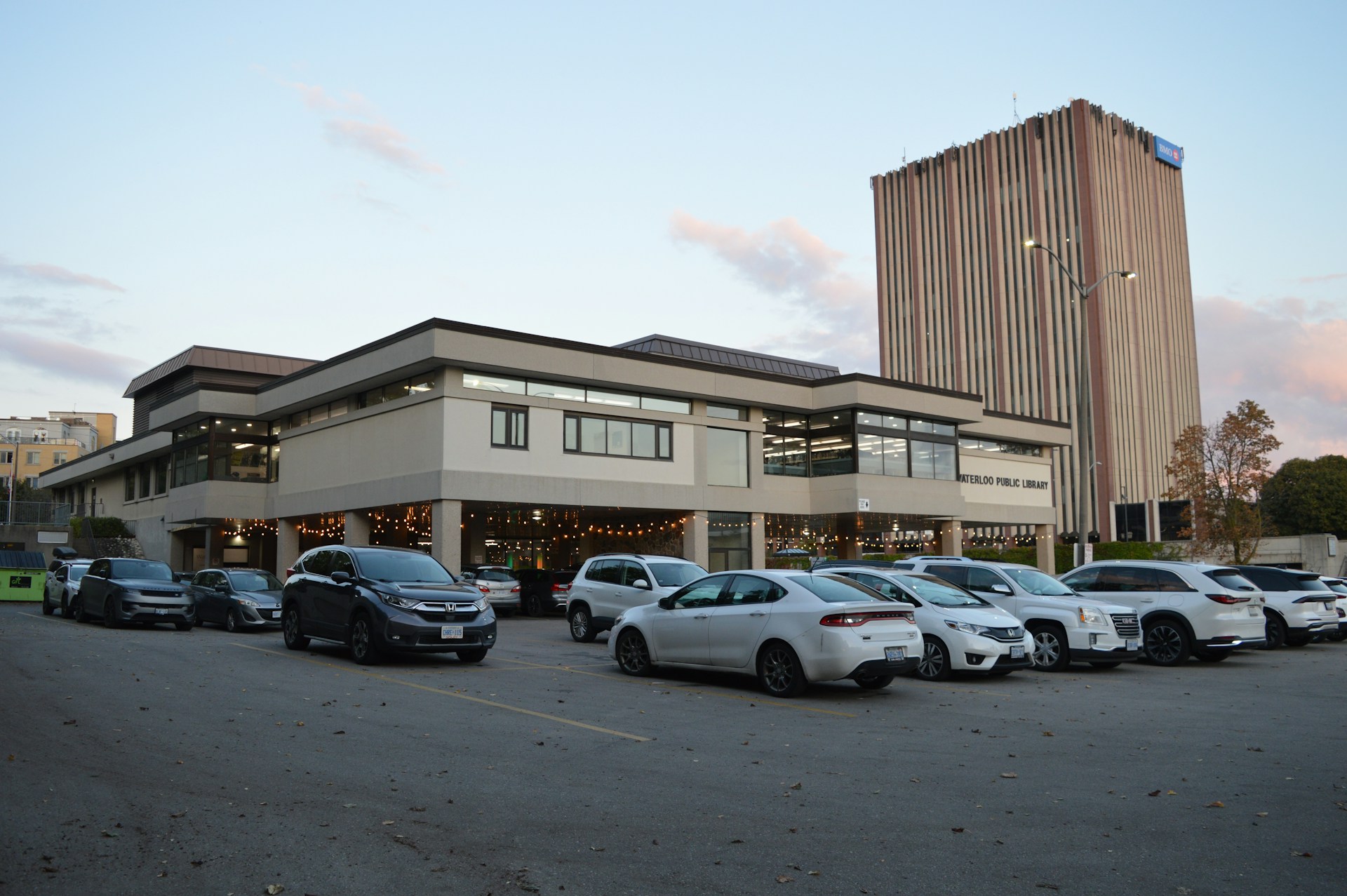 Cars parked outside a modern building with a tall tower.
