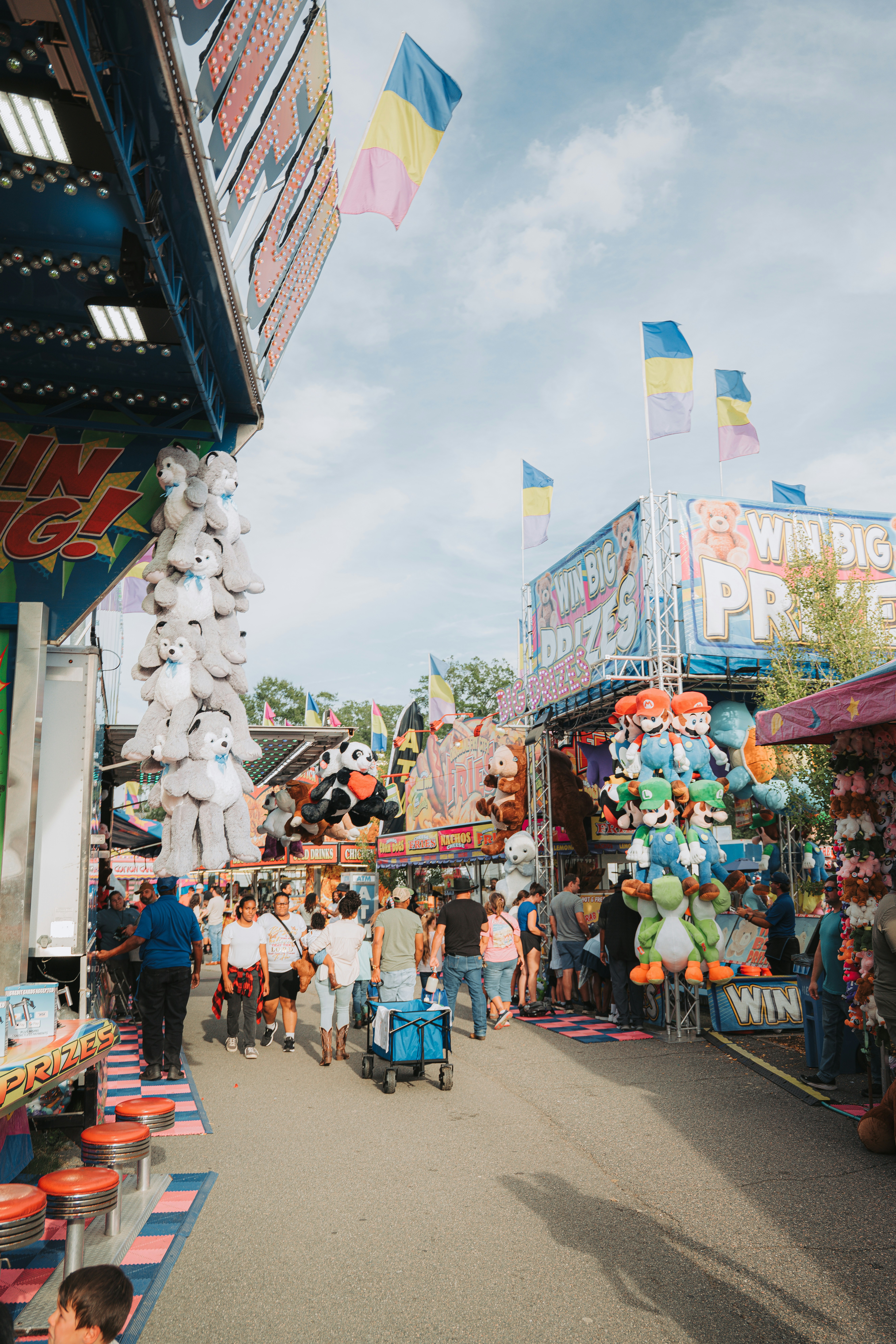 ゲームブースが並ぶ混雑したカーニバルの中を歩く人々。