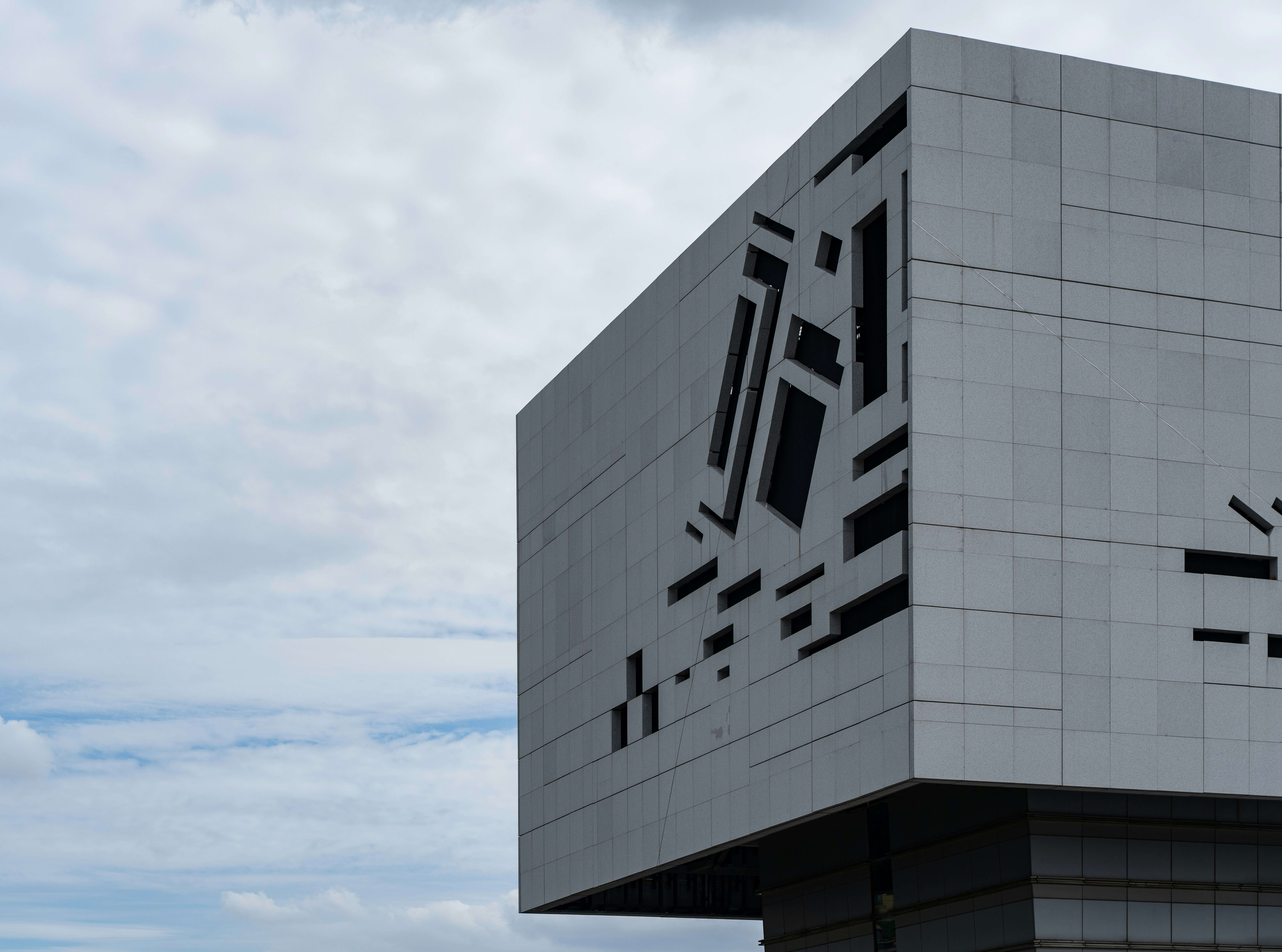 Modern building with geometric cutout facade against sky