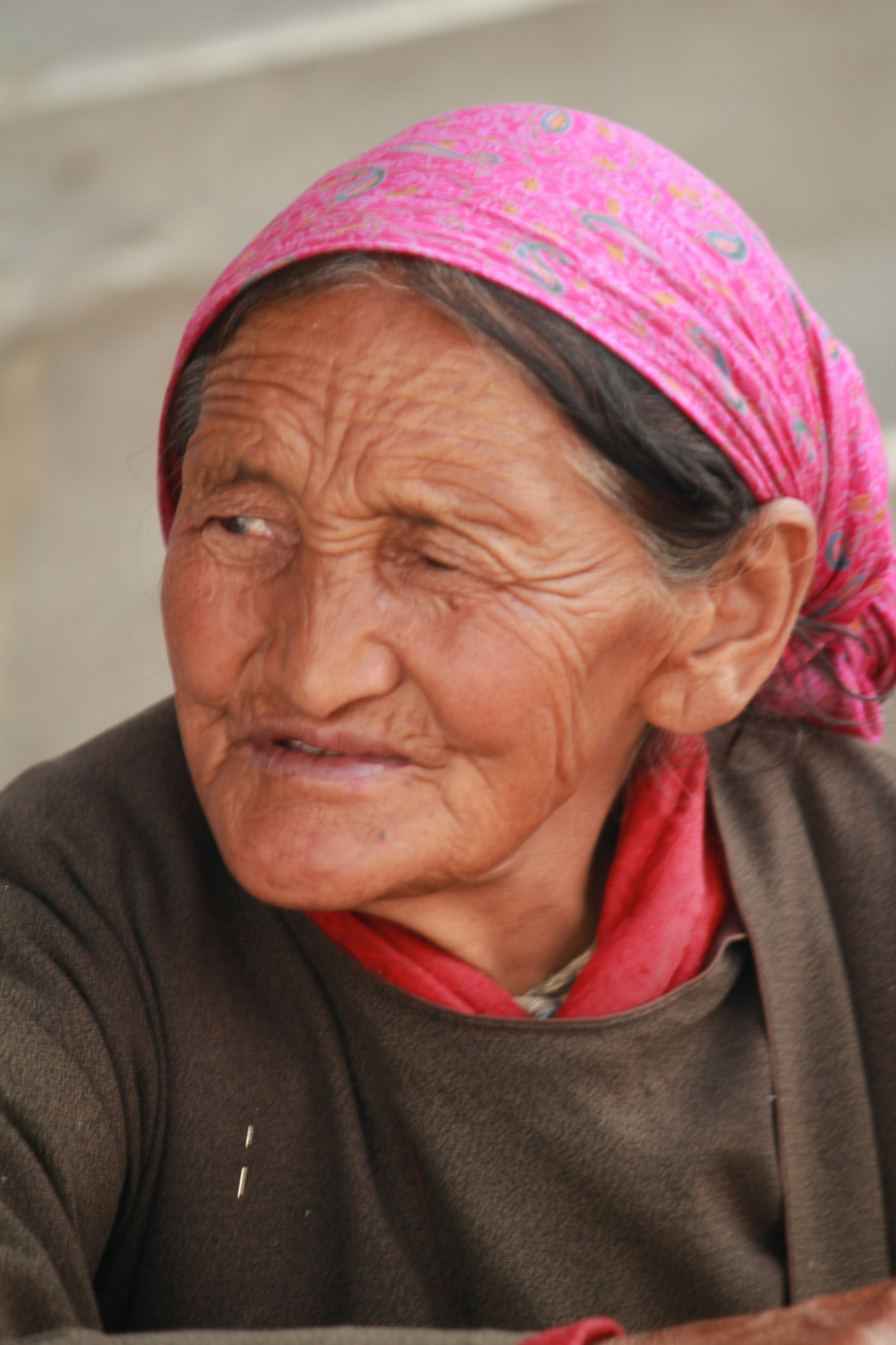 Elderly woman with a pink headscarf looking away