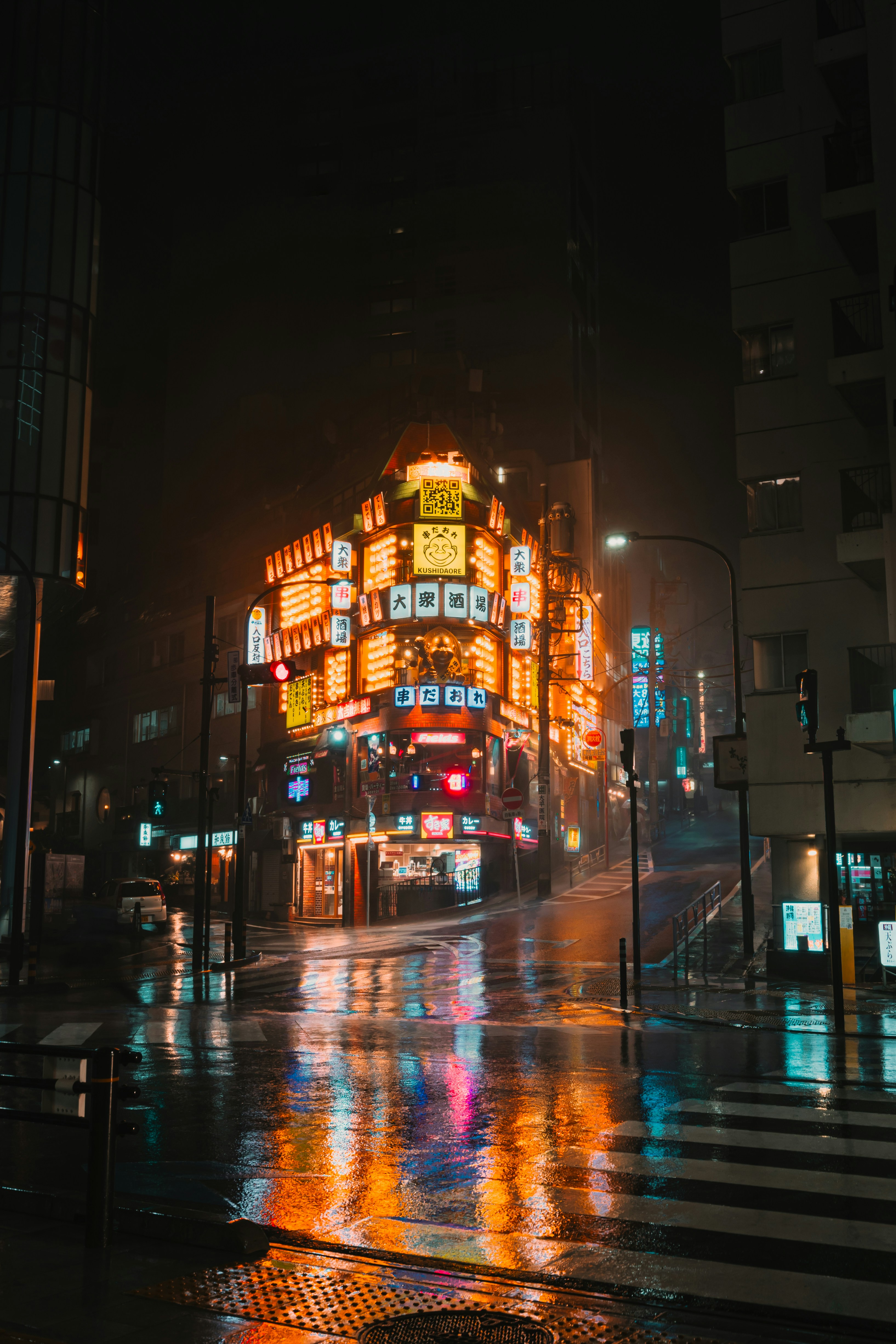Bright neon signs illuminate a wet city street at night.