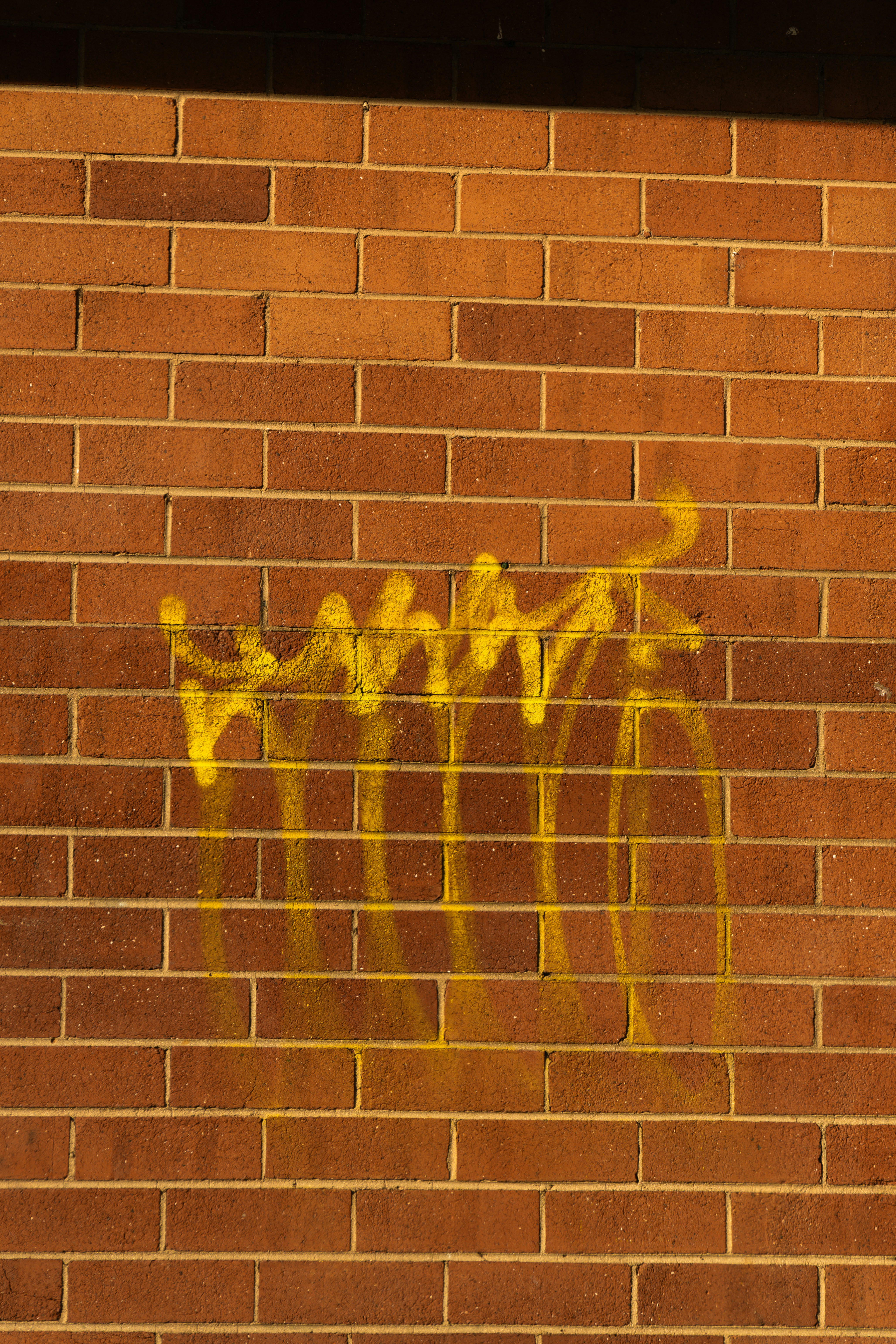 Yellow graffiti spray painted on a brick wall.