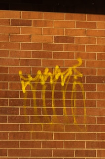 Yellow graffiti spray painted on a brick wall.