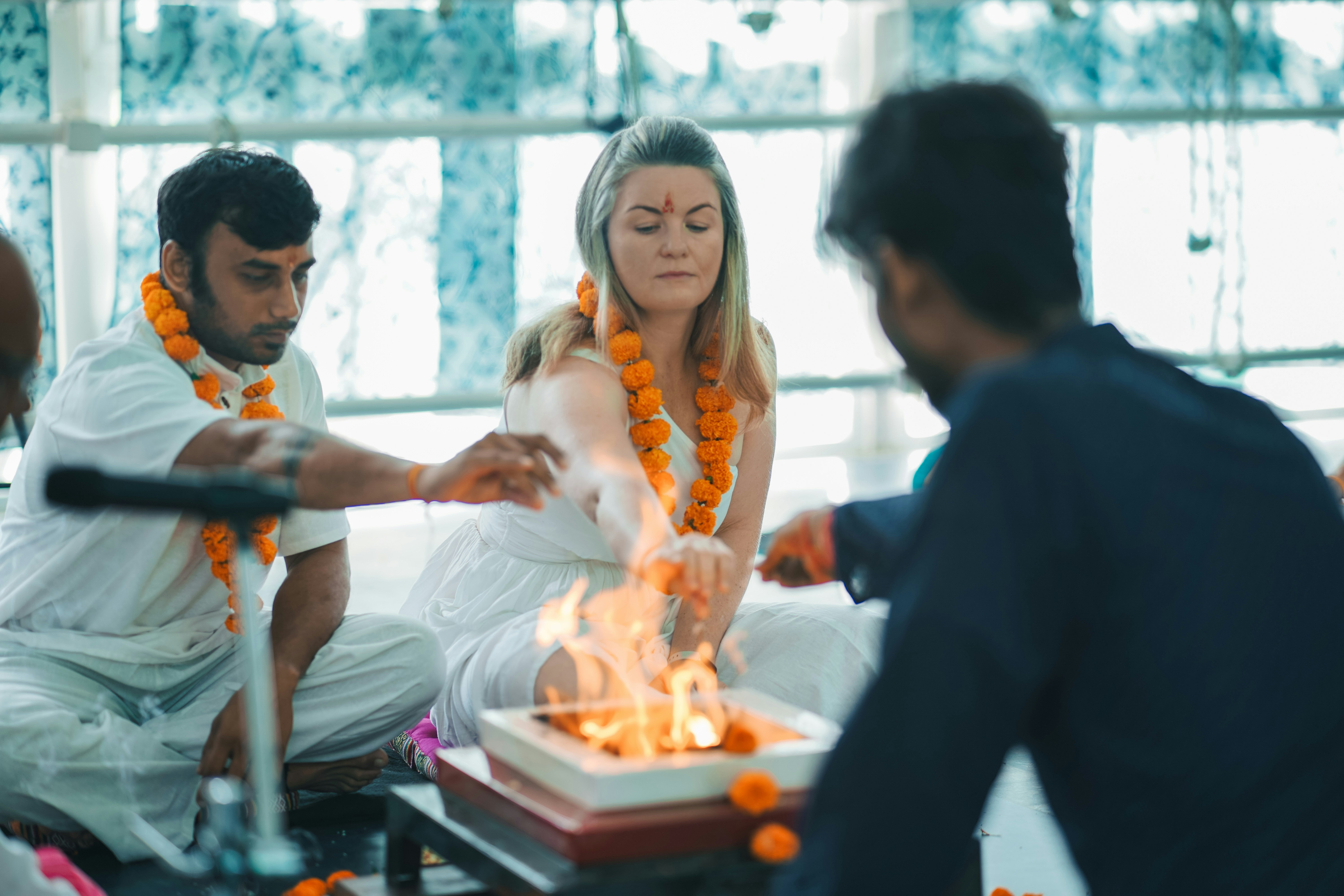 People performing a fire ritual with marigold garlands.