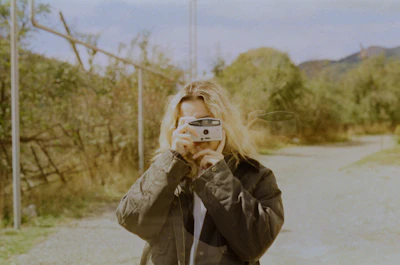Woman taking a picture with a vintage camera outdoors.