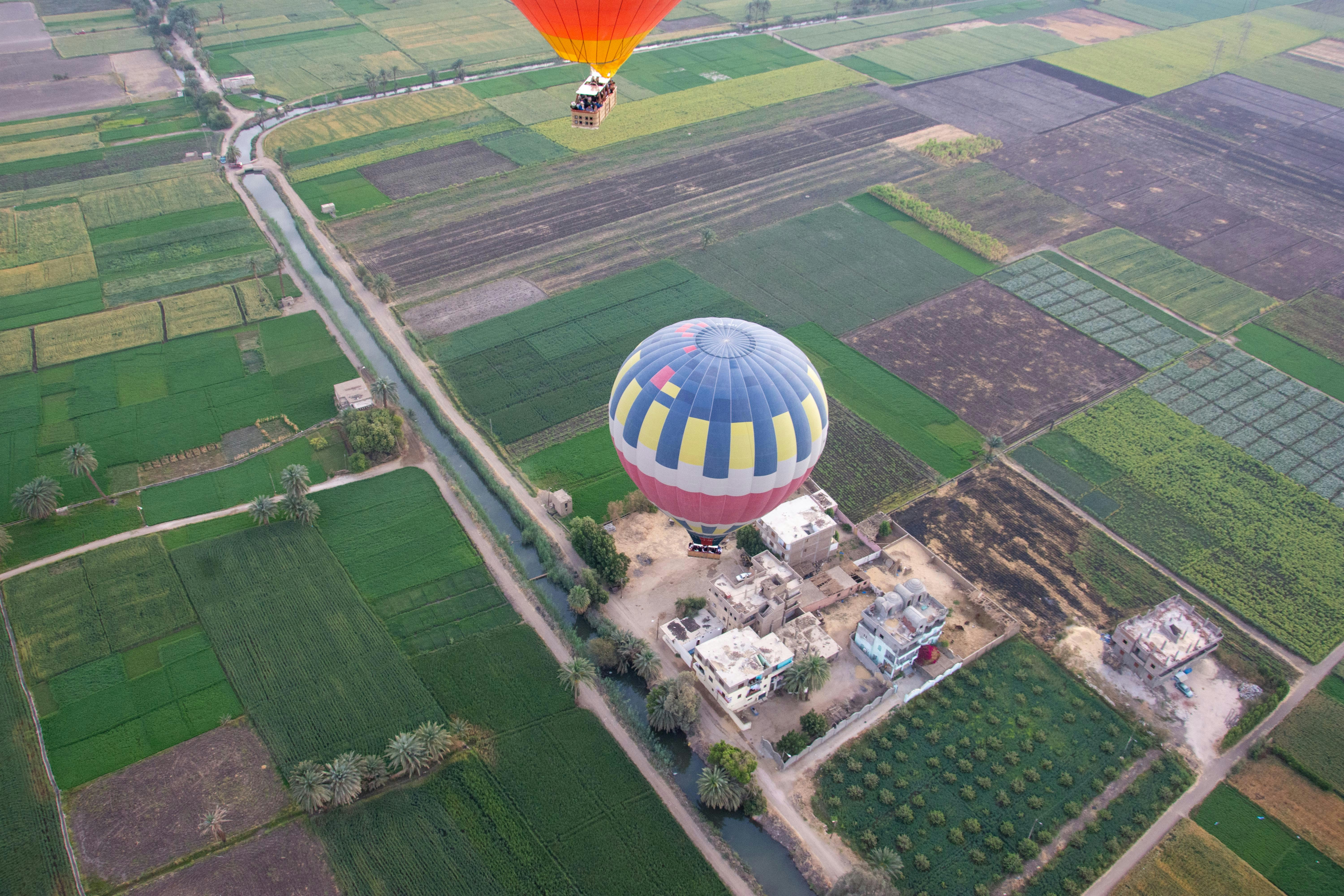 Hot air balloons flying over farmland