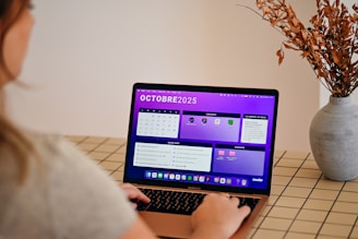 Woman using laptop with october 2025 calendar displayed.