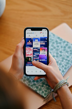 Mains tenant un téléphone affichant un flux de réseaux sociaux