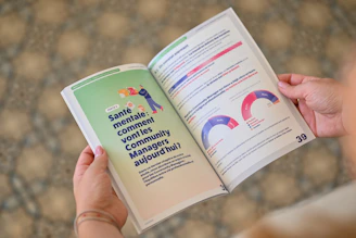 Person holding an open booklet with text and charts.